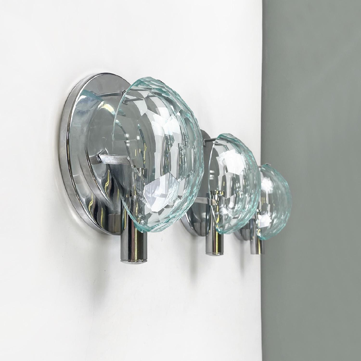 Italian mid-century modern chromed metal and faceted glass wall light, 1960s
Set of three round wall sconces. The circular base corresponds to a cylindrical structure that acts as a lamp holder, all in chromed metal. The glass lampshade is round and