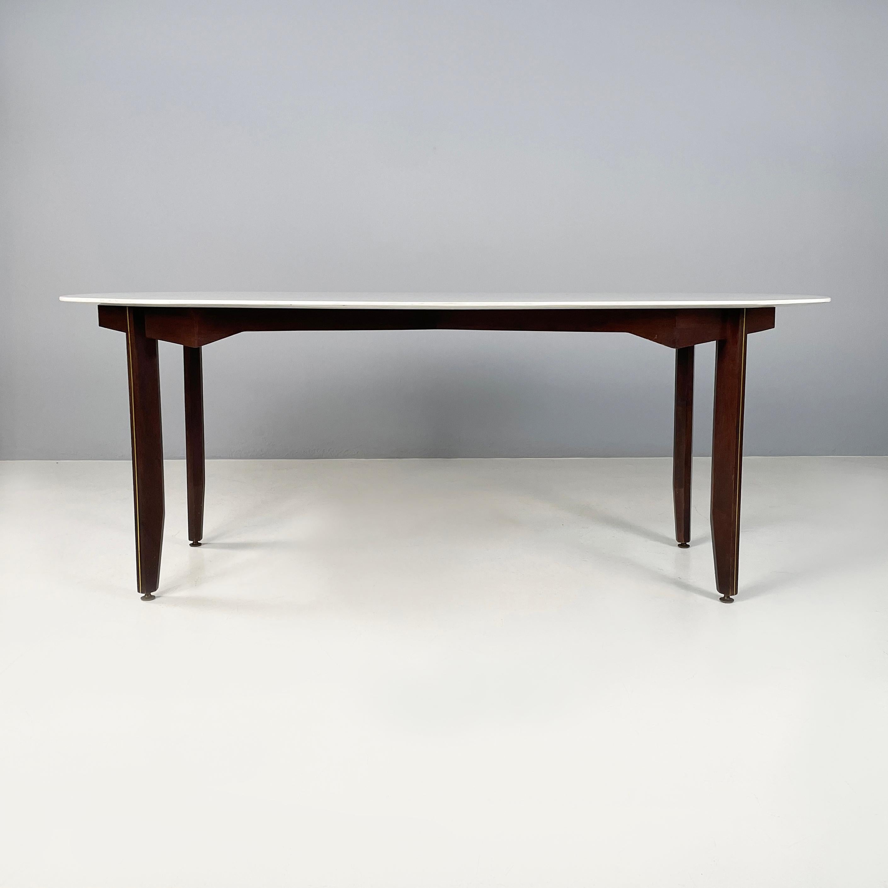 Italian mid-century modern Dining table in marble, wood and bass, 1960s
Dining table with oval top in white Carrara marble. The structure on which the top rests is an 8 shape in dark wood. The square wooden legs have brass rod details. Round brass