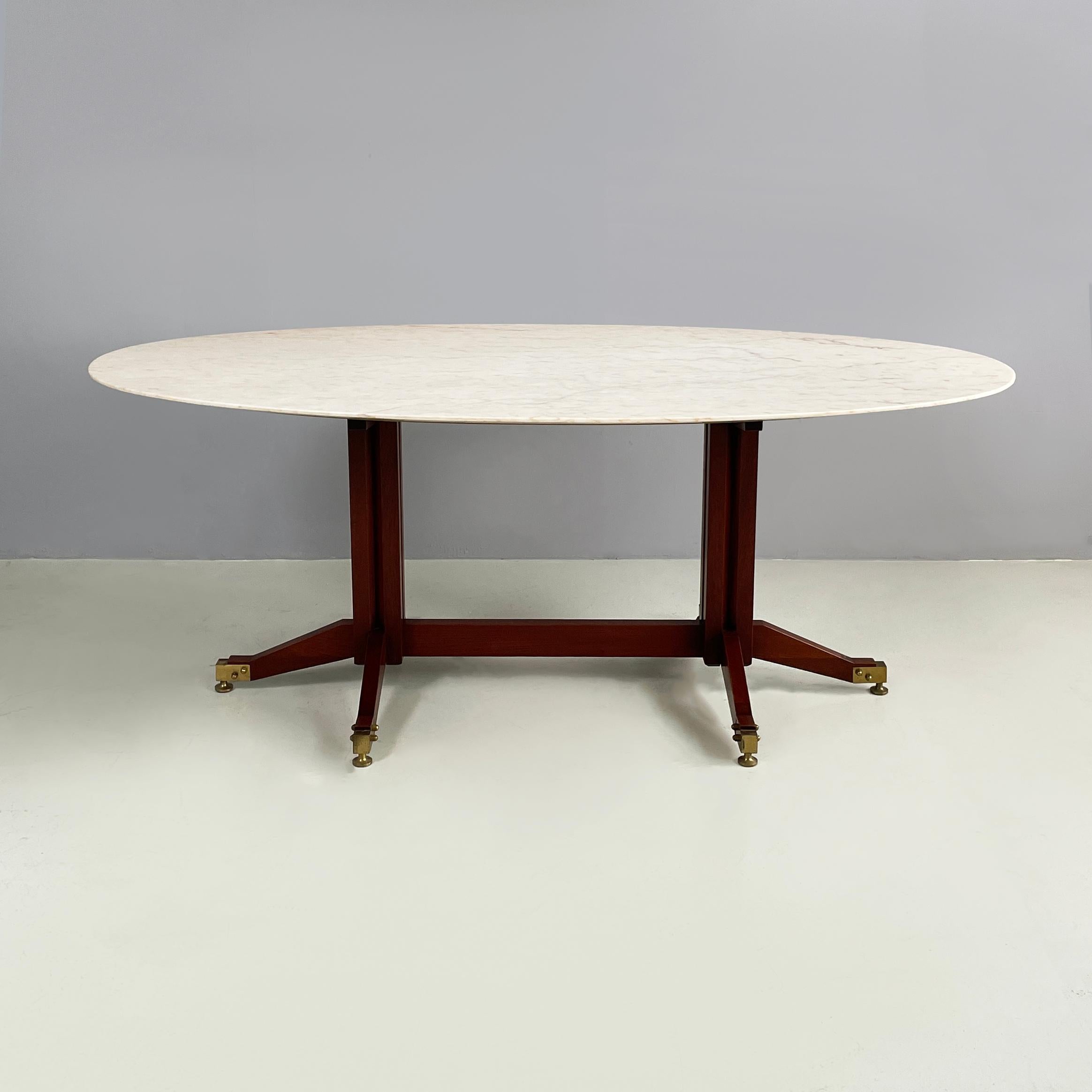 Table de salle à manger italienne du milieu du siècle en marbre, bois et laiton, années 1960
Table de Whiting avec plateau ovale en marbre clair, dans les tons blanc crème et rose pâle. La structure sur laquelle repose le marbre est en bois foncé :