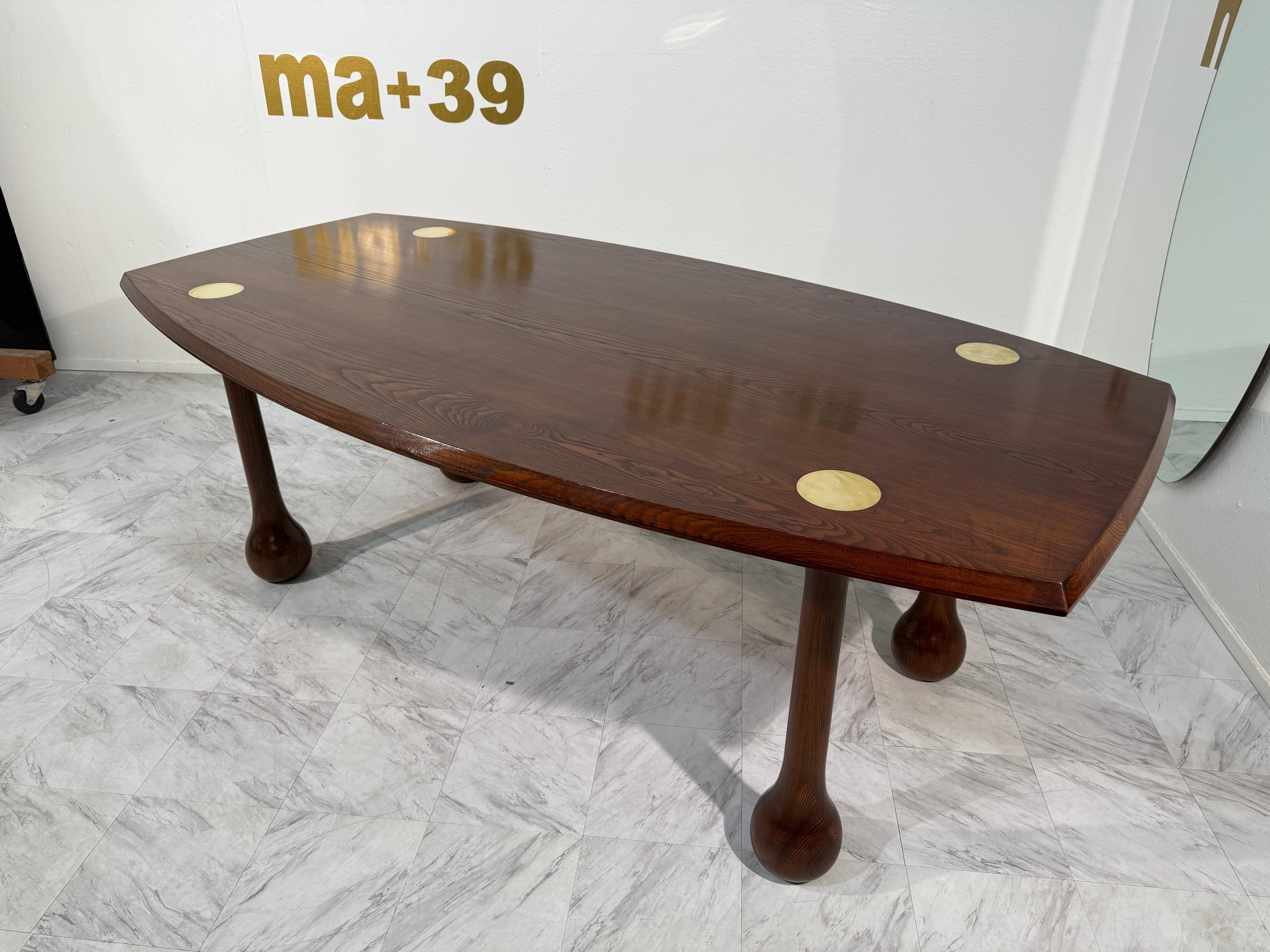 Un tavolo da pranzo scultoreo italiano del Mid-Century Modern, che si distingue per la sua forma organica e l'audace artigianalità. Il tavolo è realizzato in legno di frassino tinto a grana fine, con un piano rettangolare dolcemente curvato e