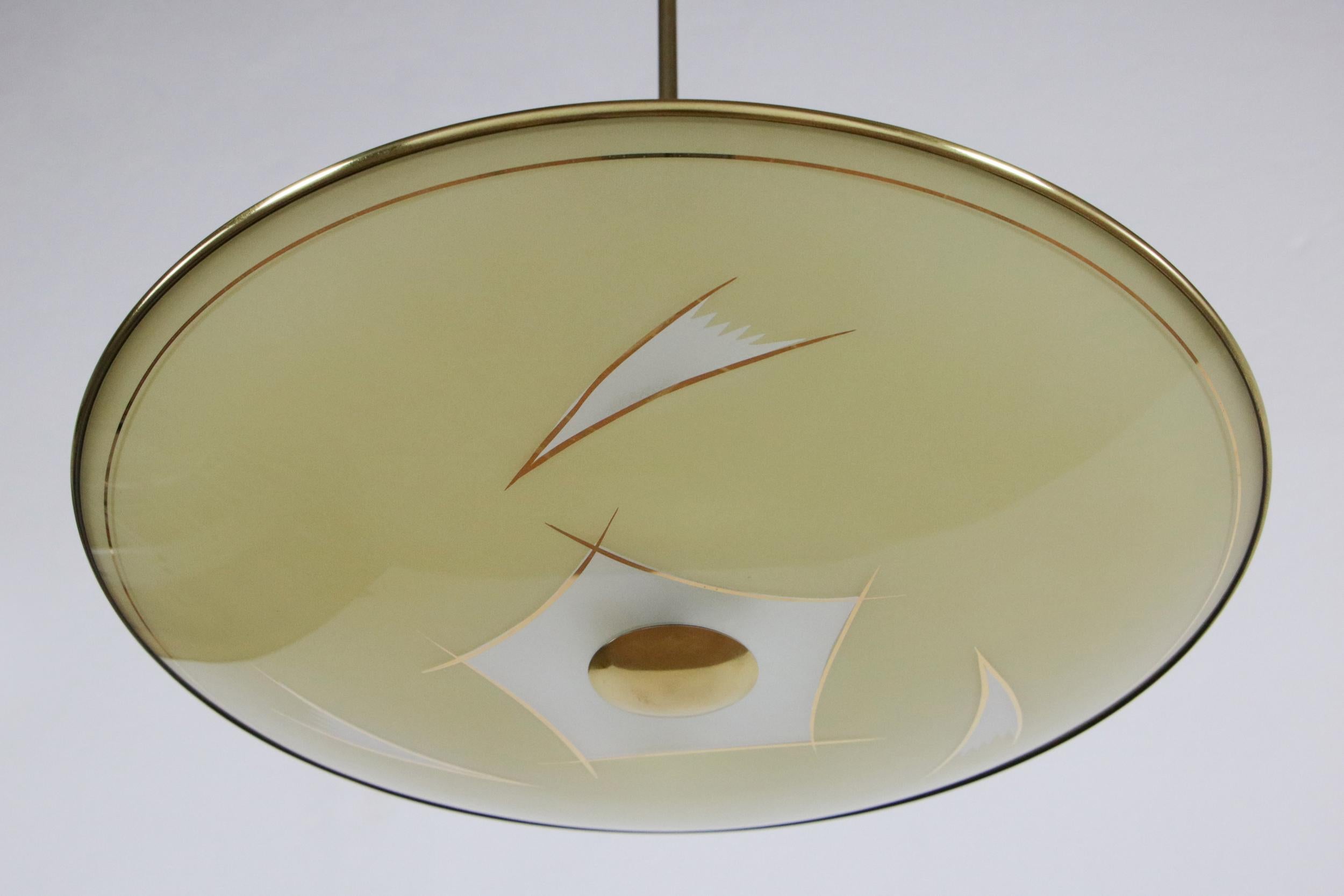 This beautiful Italian Mid-Century Modern disc chandelier or pendant lamp is made of brass and sandblasted glass. It has two lights of E14 format. The delicate hand drawings are what give this lamp such a distinctive character. We recommend viewing