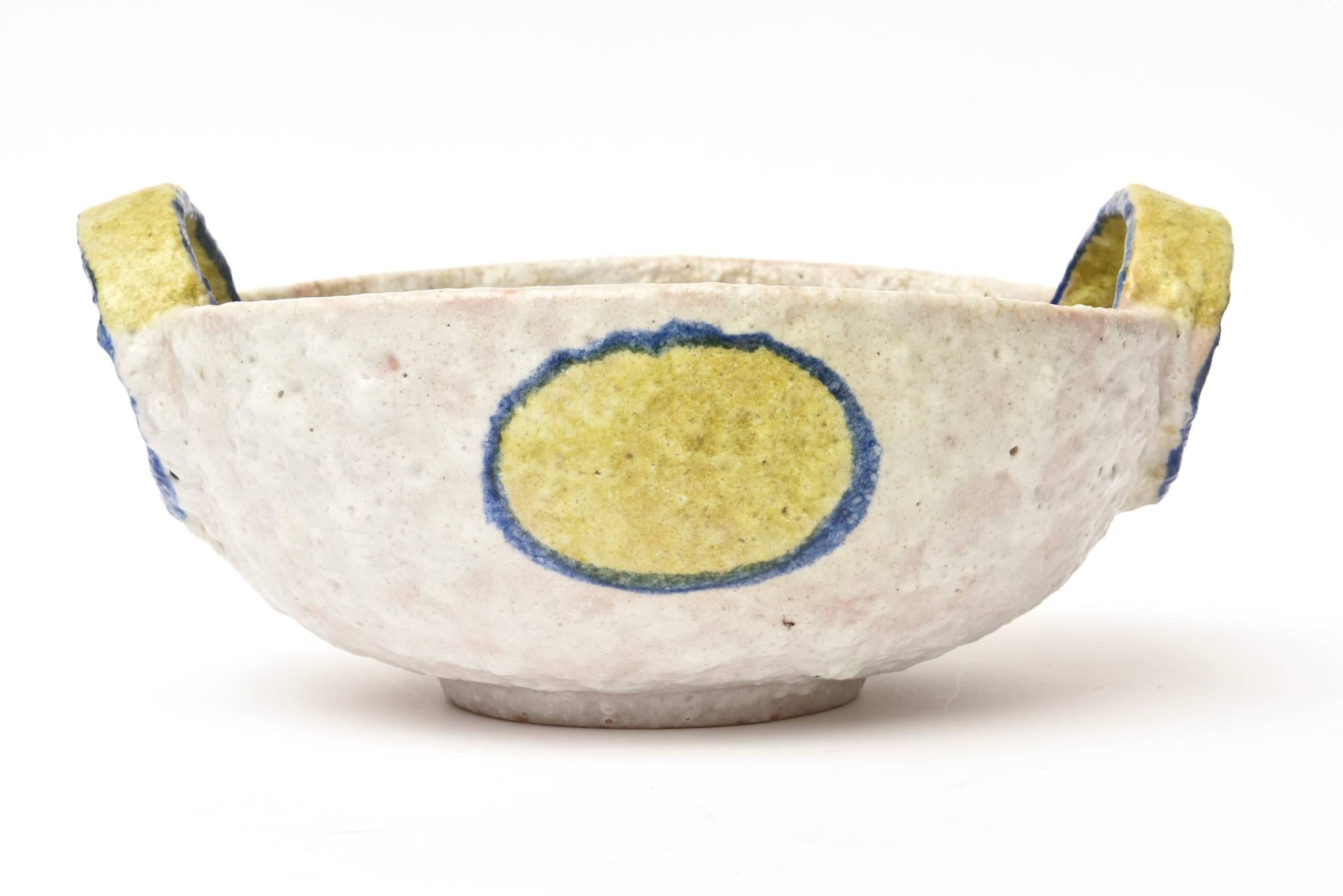 This sculptural and unusual Italian ceramic bowl by Fantoni for Raymor bowl has an unusual color palette with pebbled textural surface. It is marked Italy Raymor on the bottom with numbers. The height to the top not the handle top is 5.5