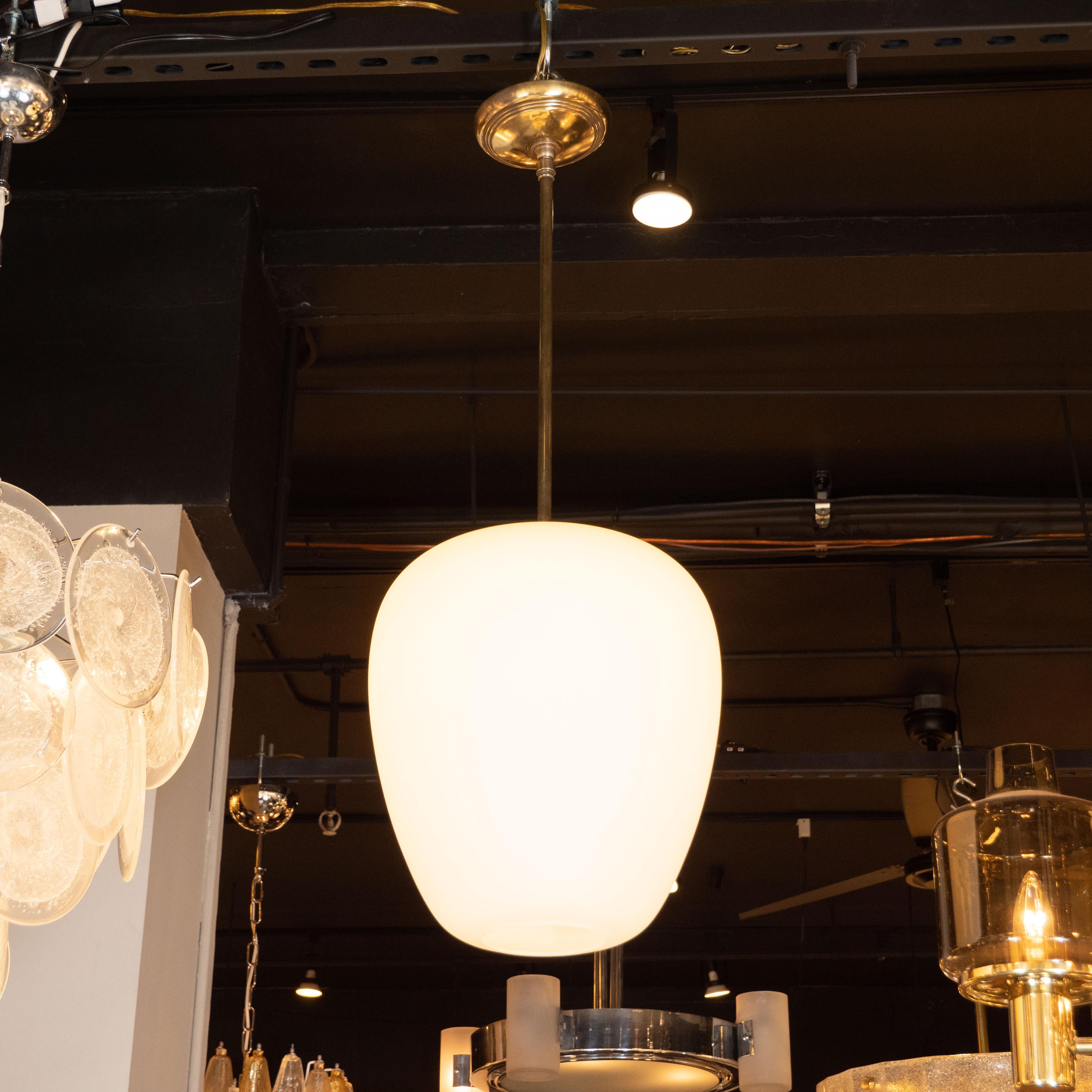 This elegant Mid-Century Modern pendant was realized in Italy, circa 1960. It features a gently tapered conical body with rounded shoulders in frosted glass suspended from a circular brass canopy via a cylindrical rod in the same material. With its