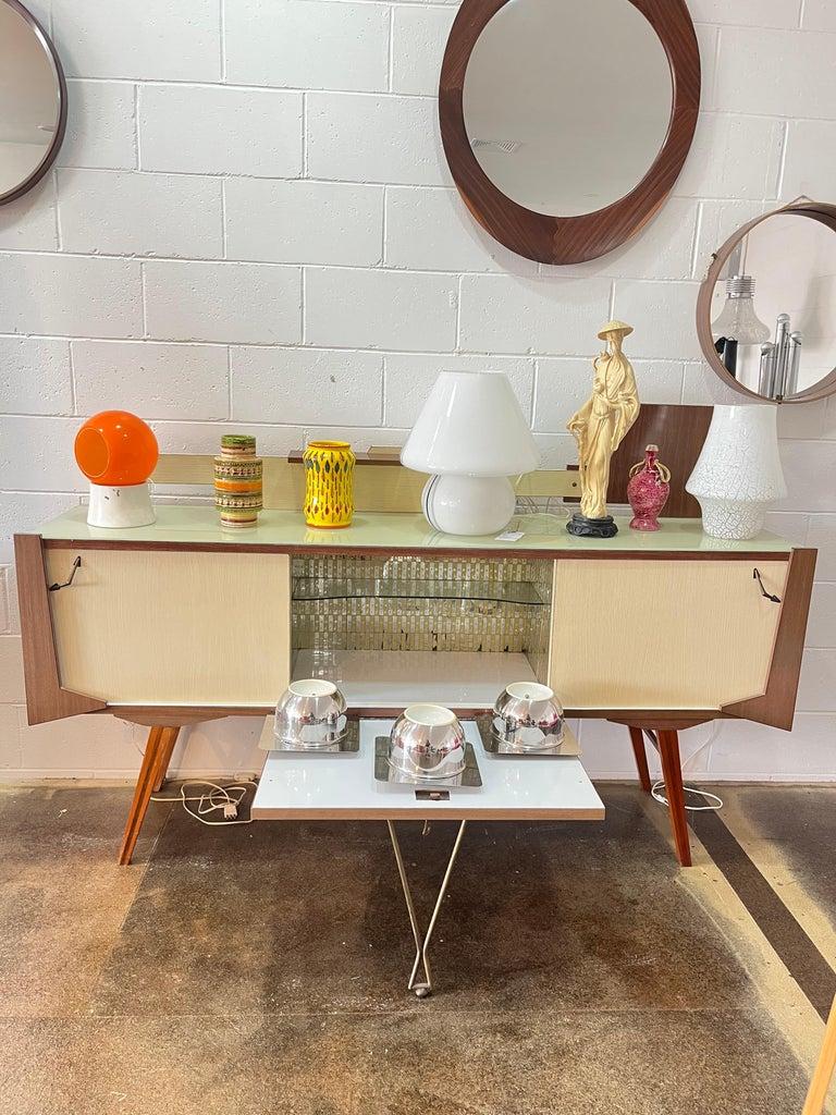 Credenza originale italiana funky Mid-Century Modern con bar all'interno situata nella parte centrale del mobile. Il bar ha un interno luminoso ed è realizzato con un'elegante opera d'arte in vetro che ricopre le pareti del locale.