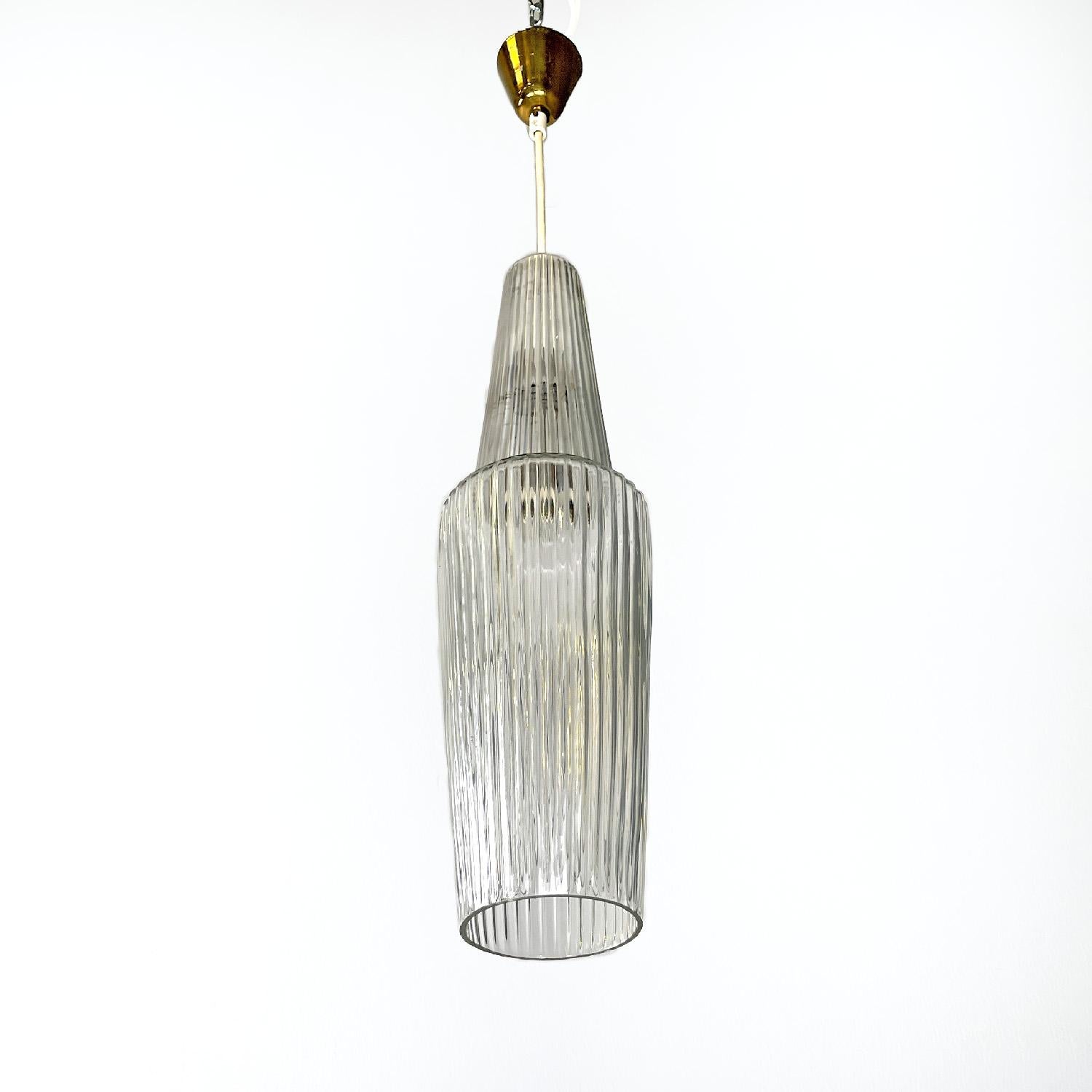 Italian mid-century modern golden plastic and fluted glass chandelier, 1950s
Round glass base chandelier. The diffuser is elongated with a vertical geometric texture, in the central part the glass narrows creating a step. The ceiling attachment is