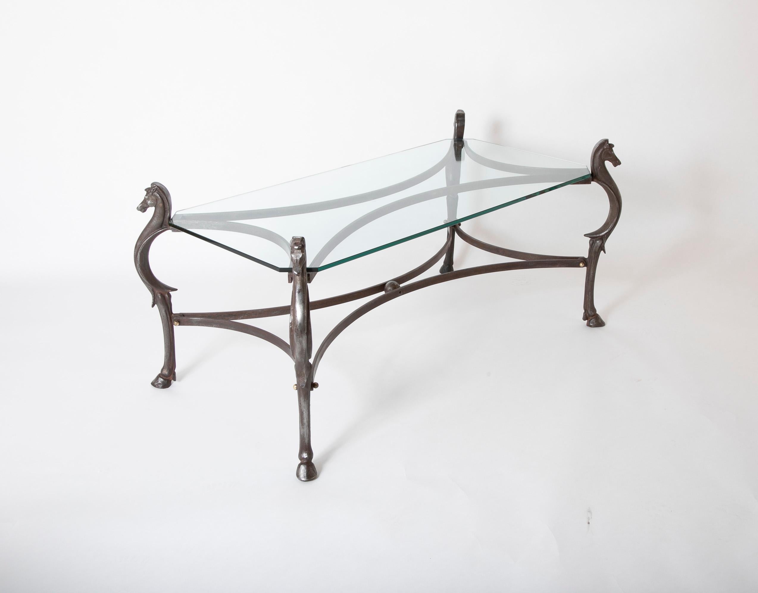 Fantastic Italian iron and glass coffee table with four supports in the form of a horse legs topped by horse heads in a beautifully realized design. All joined by two sets of curving stretchers joined by brass ball terminals. Wonderful patina. Circa