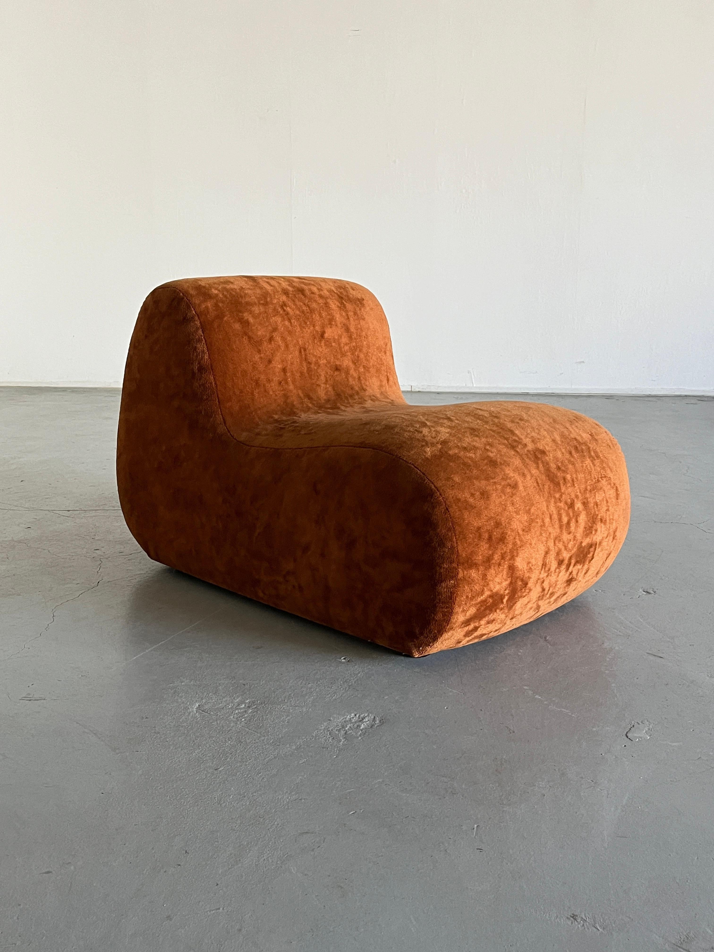 Vintage mid-century modern lounge chair or club chair upholstered in rich brownish orange velvet fabric. The plush, comfortable cushioning and the stylishly curved design make it an ideal piece for relaxation. Produced in Italy during the