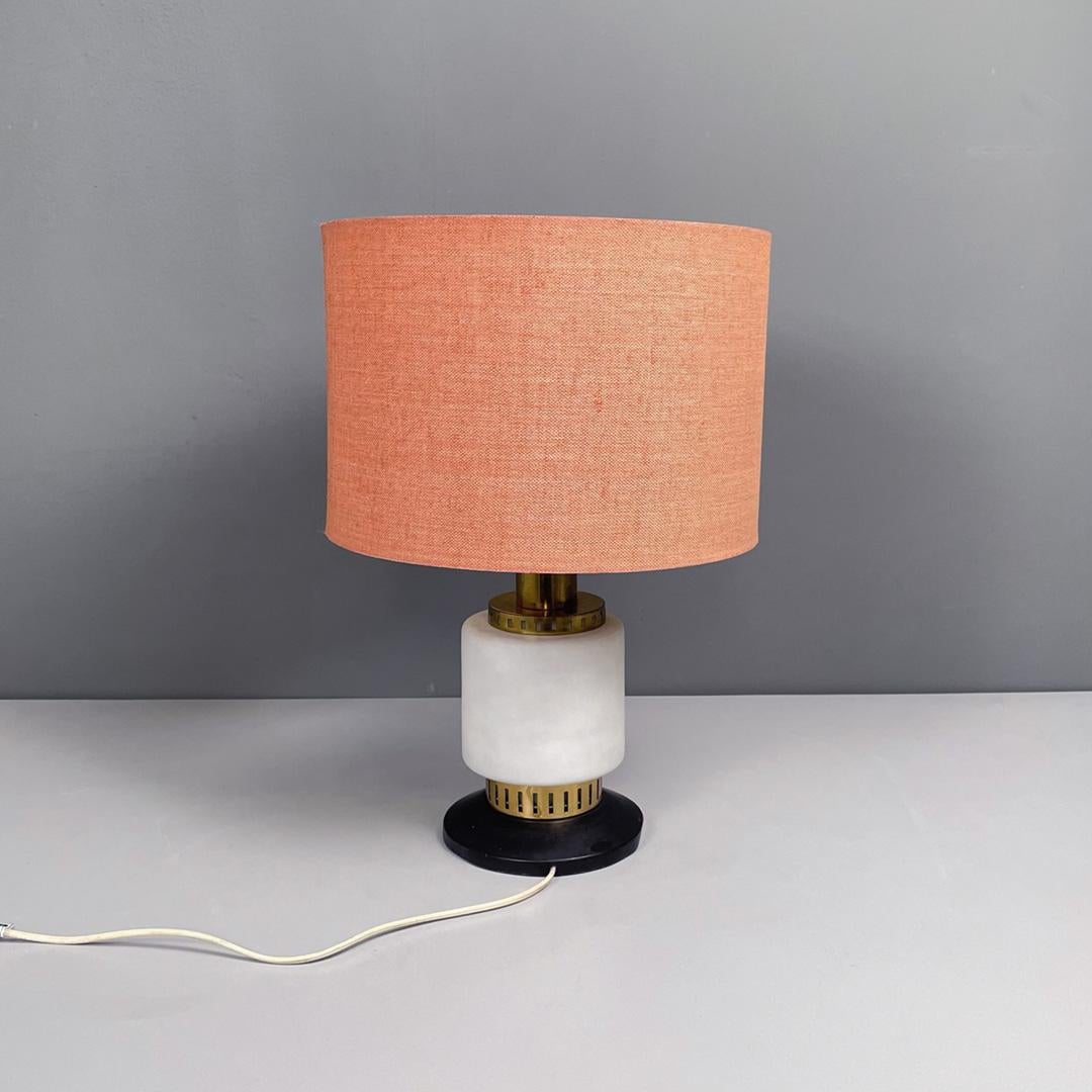 Italian mid-century modern metal fabric and glass table lamp by Stilnovo, 1960s
Table lamp with round base in black metal. The cylindrical body is in white opal glass, the upper structure is in brass and the circular lampshade is covered in orange