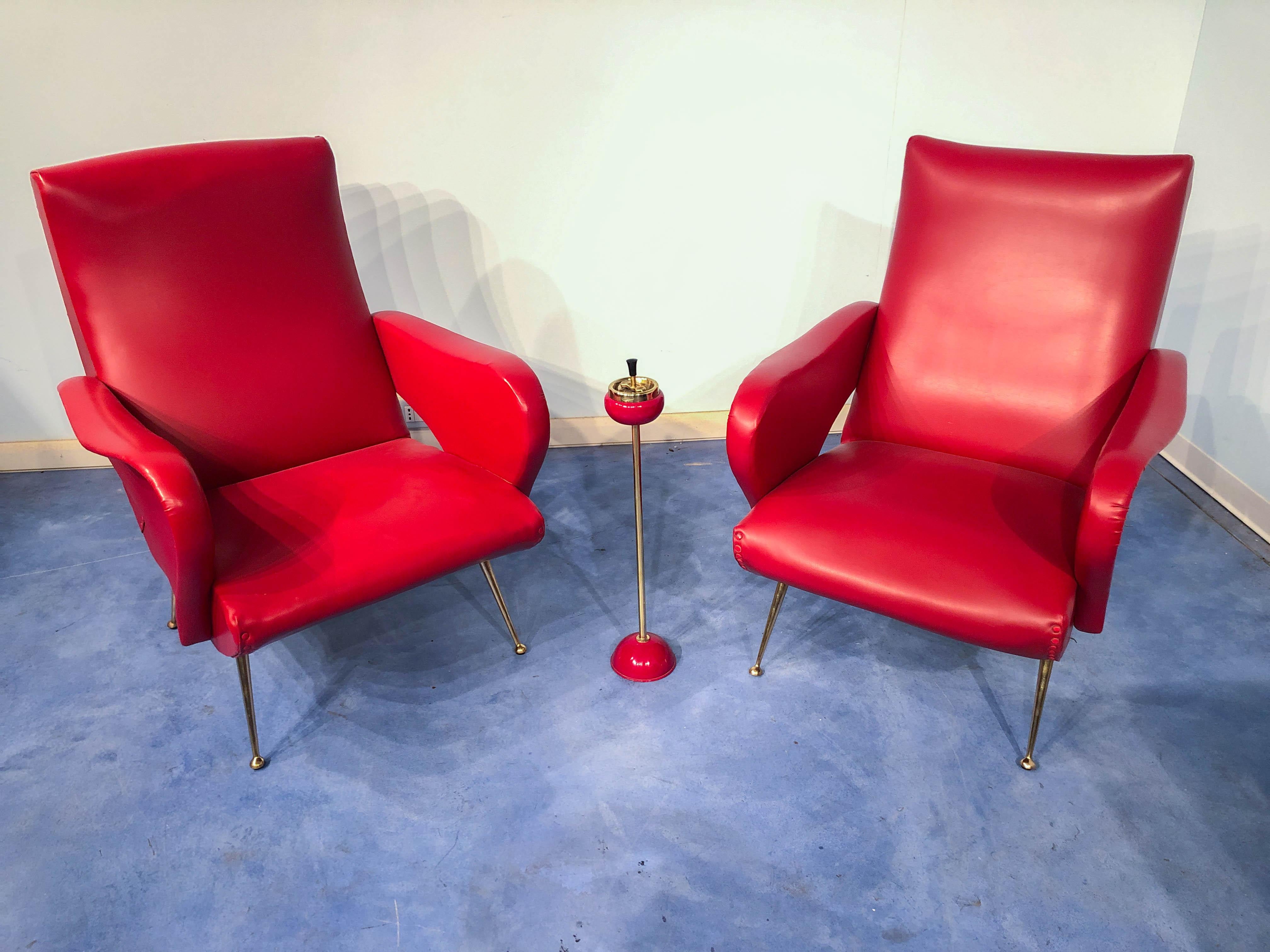 A pair of stylish and comfortable Italian Mid-Century Modern red vinyl armchairs or club chairs in Nino Zoncada Style, 1950.
In very good vintage condition, polished the brass feet and cleaned the surface. 
As you can see from the pictures it also