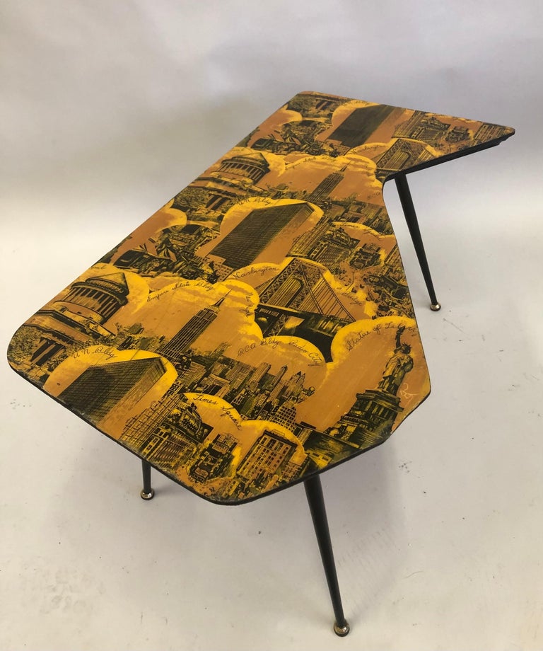 Italian Mid-Century Modern coffee table attributed to Piero Fornasetti. The table suspended on 4 angled black metal legs with a dynamic screen printed and lacquered top featuring the landmarks of New York City, circa 1950. The landmarks include the