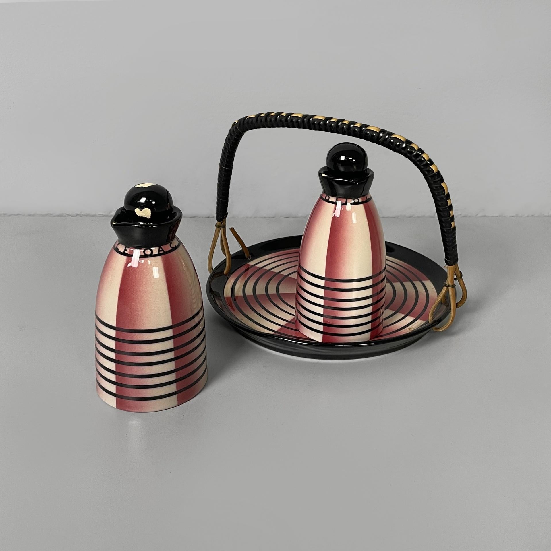 Set à huile et vinaigre en céramique avec plat de service. Les deux bouteilles en céramique à base ronde présentent une décoration à bandes verticales rouges et blanches et à bandes horizontales noires. Les deux ont des capuchons noirs. Le plat de