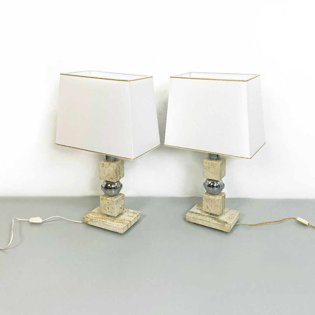 Italian Mid-Century Modern pair of steel and travertine table lamps, 1970s
Pair of table lamps in travertine and steel, with cubic stem and alternating spheres and rectangular base also in travertine. White truncated pyramid lampshades with golden