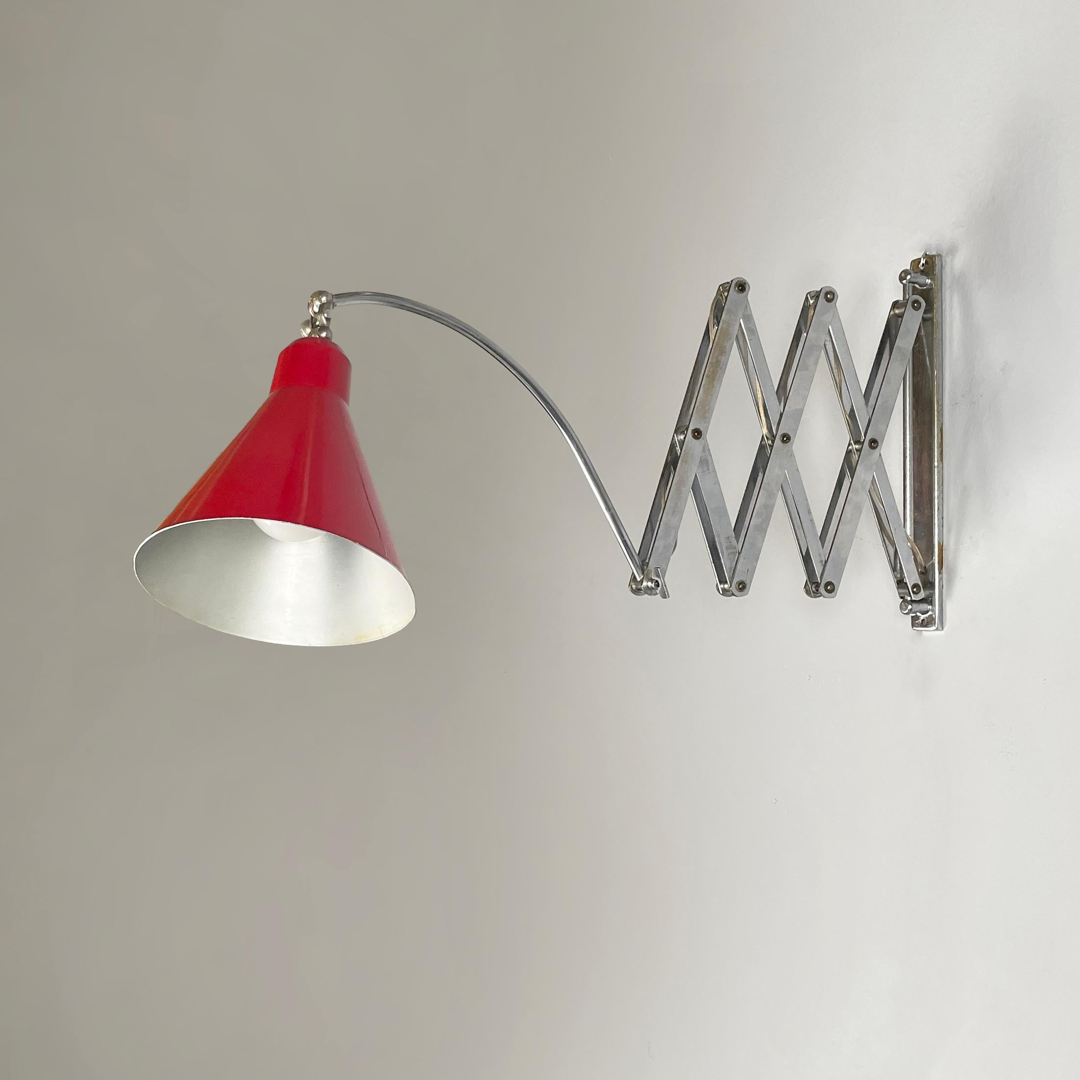 Lampada da parete Pantograph, in metallo rosso, 1960
Lampada da parete a pantografo con struttura a bracci metallici regolabili. Il paralume conico regolabile in metallo verniciato rosso è collegato alla struttura del braccio grazie a un'asta