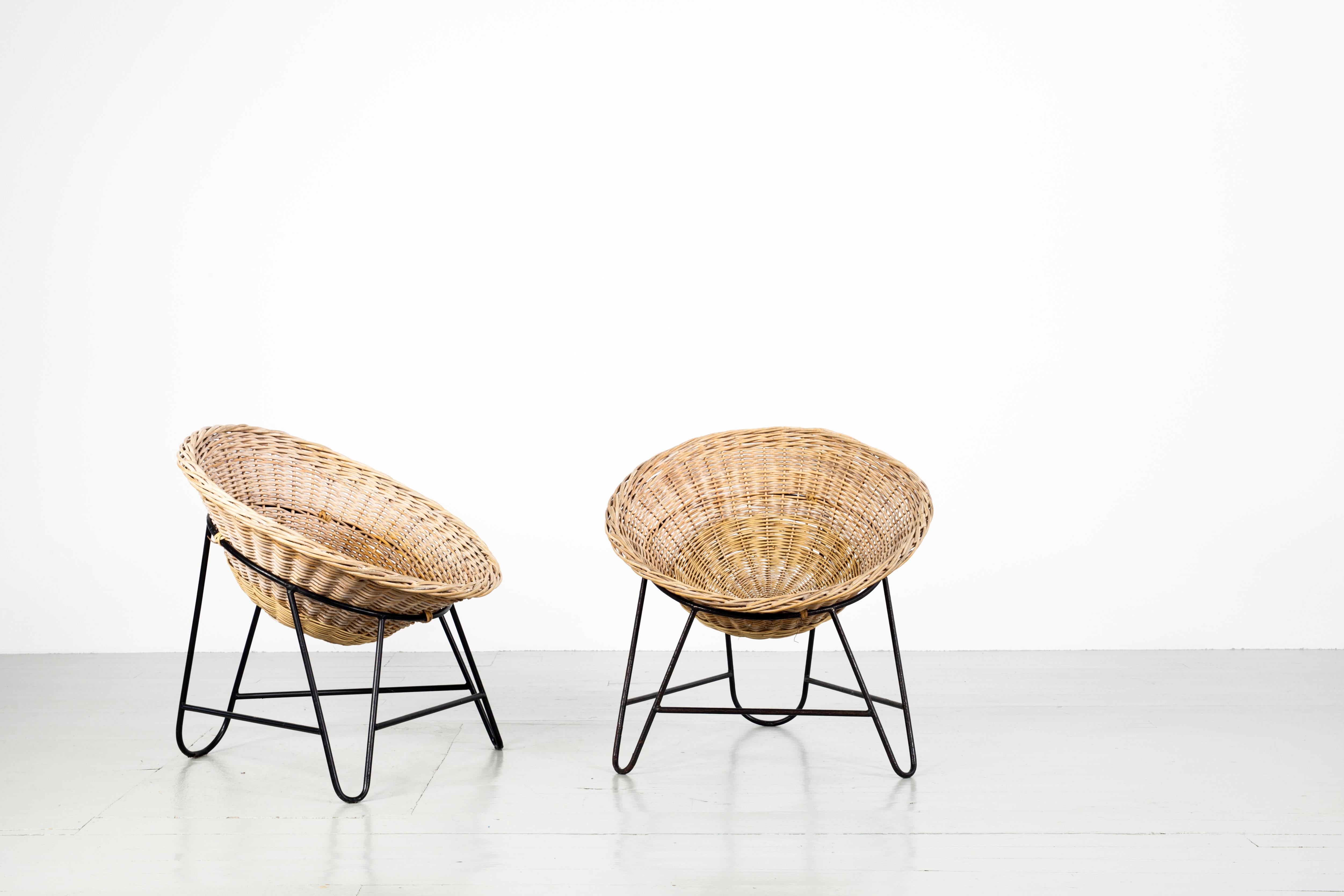Italian Mid-Century Modern light brown Rattan basket chairs. The chairs are often described as coconut-shaped. They feature a light brown rattan seat shell and a base of lacquered iron. The chairs are in good vintage condition

 
