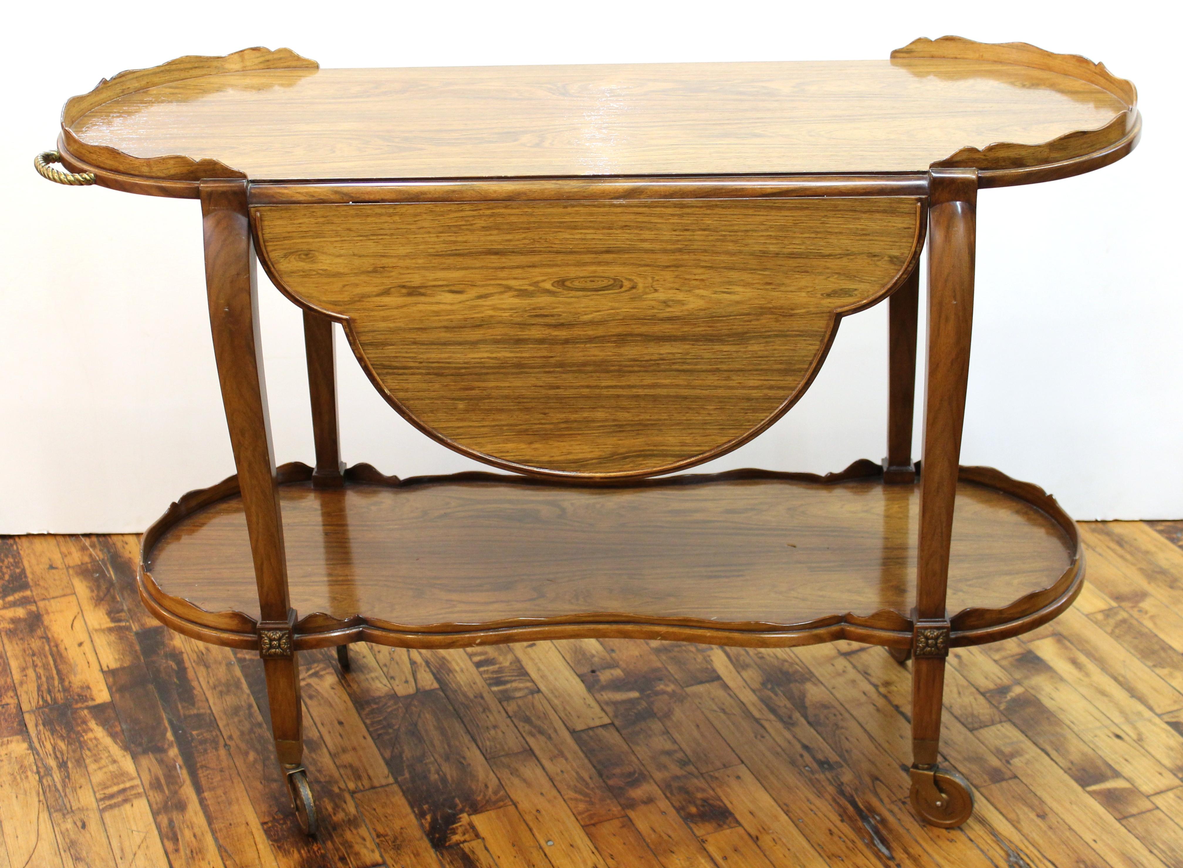 Italian Mid-Century Modern rosewood drop leaf serving cart or bar cart on wheels, with scalloped leaves that expand into an oval top. In very good vintage condition with age-appropriate wear.