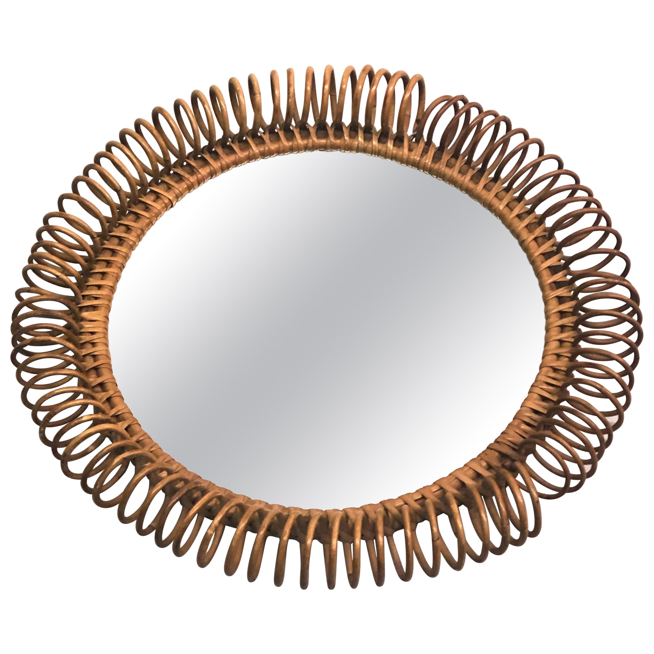 Italian Mid-Century Modern mirror in rattan attributed to Franco Albini. The mirror is round and the rattan is woven as an elegant, poetic spiral which delicately circles the frame. 

References: Jean Royère, Sunburst Mirrors, Bamboo, Wicker.
