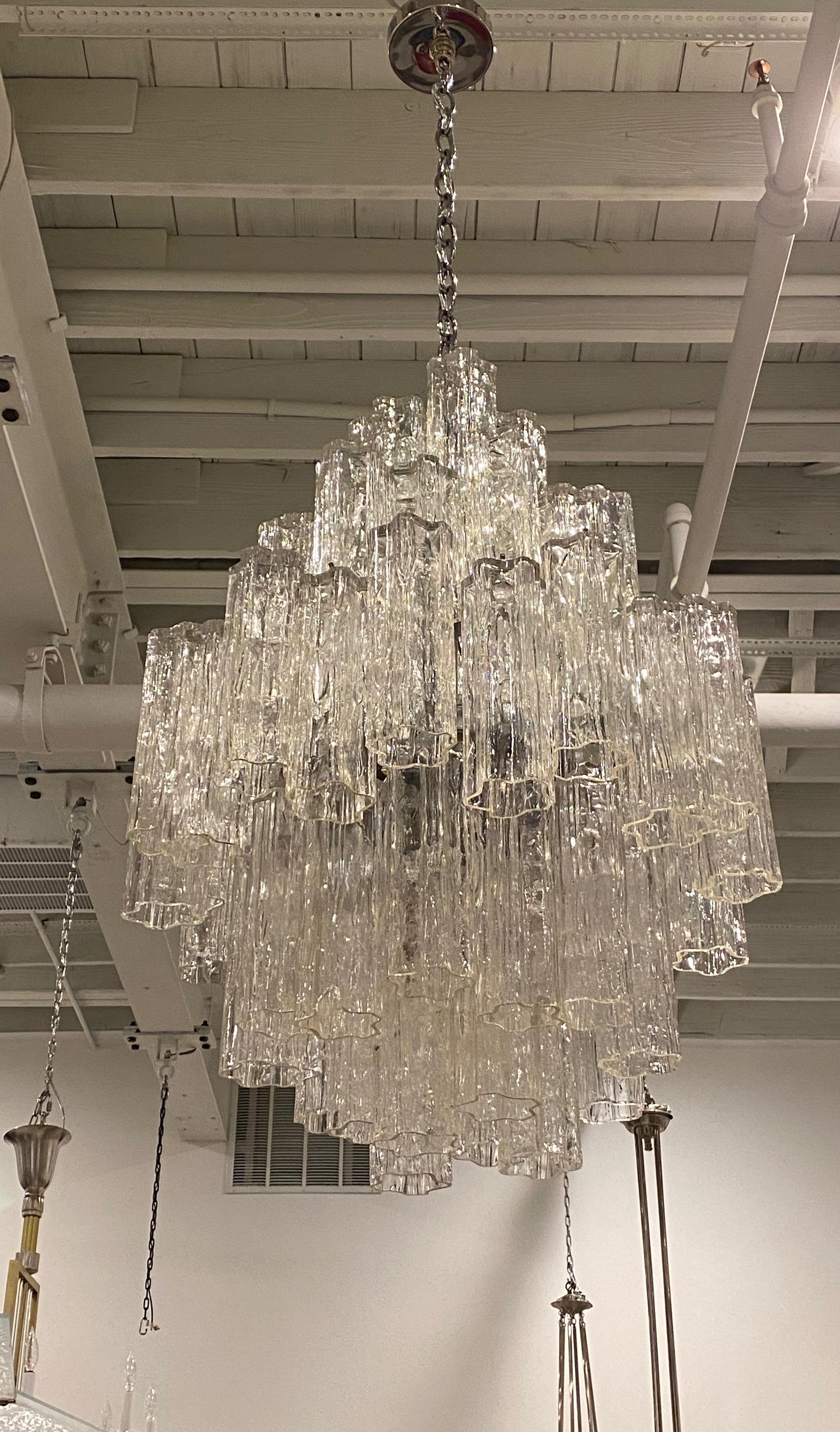 Mid-Century Modern tiered round chandelier. Consisting of tronchi cylindrical glass pieces. Each piece is hand blown and has a star or floral shape. The glass tronchi hangs from a nickel (silver) frame as pictured. Any amount of chain can be added