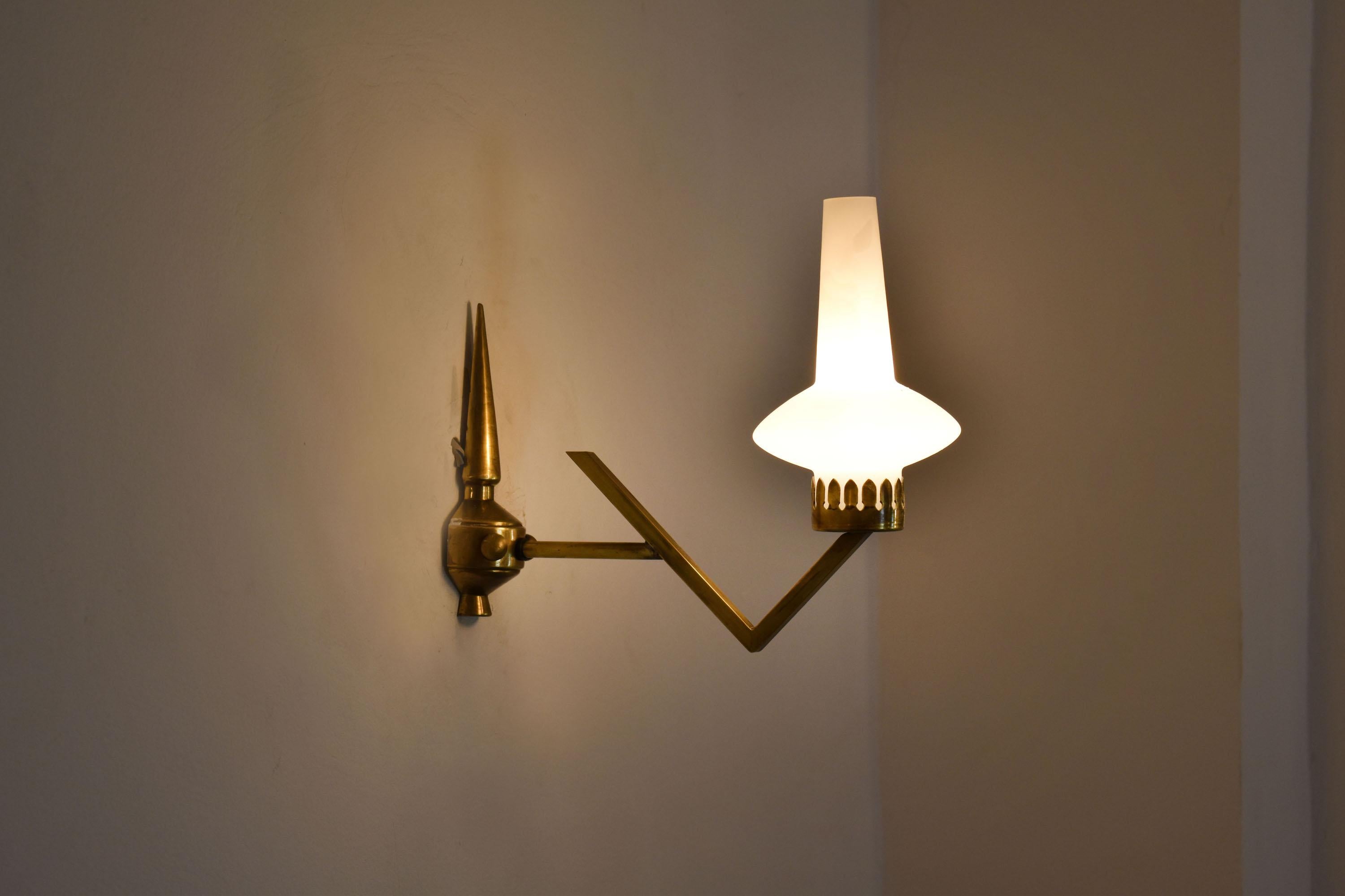 A gorgeous pair of 1950's Italian mid-century modern brass wall light or sconces. The angular solid gold brass arm and sophisticated mounting plate have a timeless sophisticated allure. 
The glass is in excellent condition. We have an extra glass