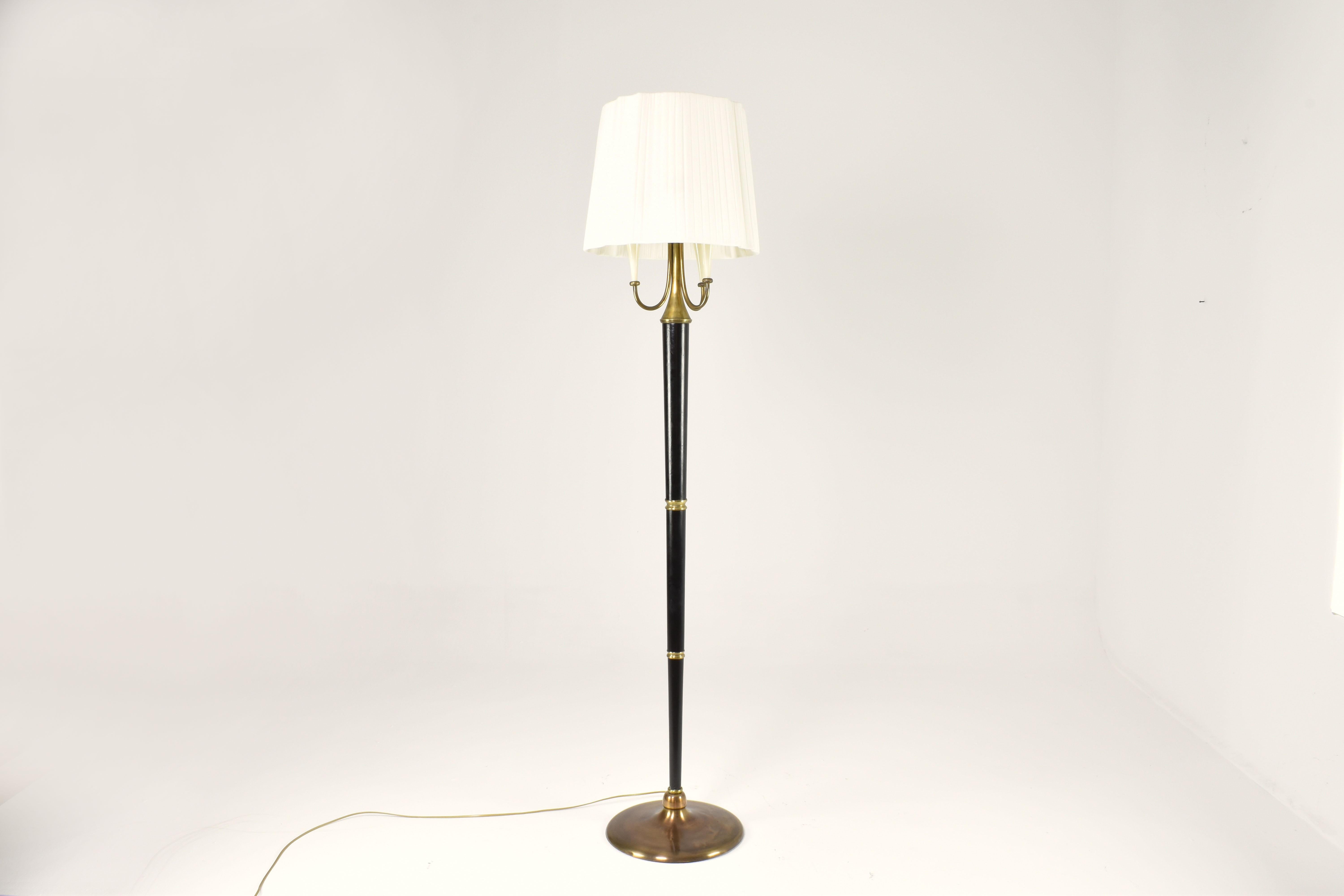 This 1950s Italian floor lamp is a beautiful example of mid-century lighting design, blending classic with post-war modernism.

Composed of three elegant torch-like arms in cream resin, the lamp is designed with an ebonized shaft, brass accents, and