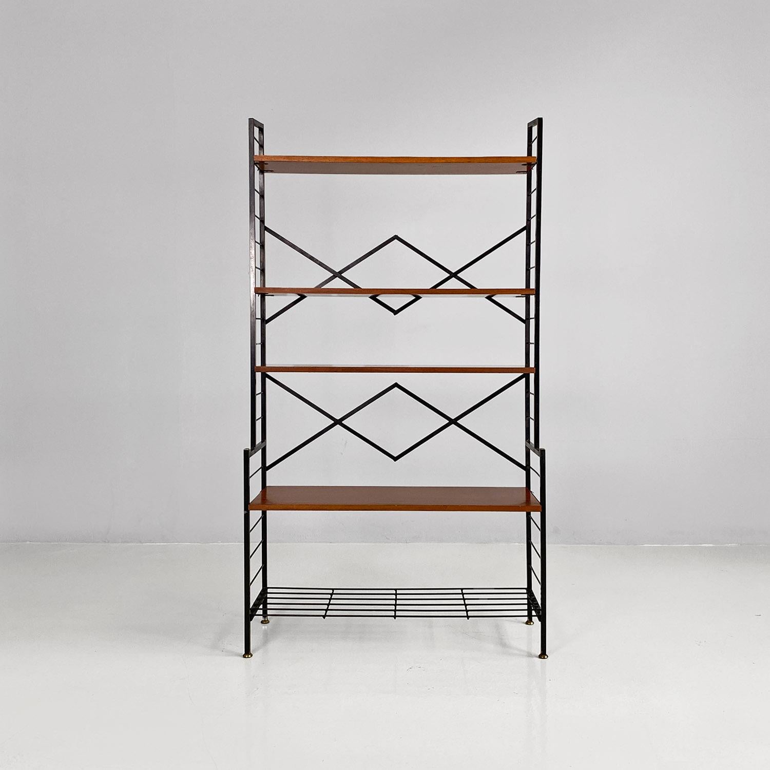 Libreria autoportante di media altezza, con struttura scatolare in metallo nero, ripiani in legno e finiture e puntali in ottone.
La struttura è autoportante, con montanti dotati di numerose aste metalliche distanti 7,5 cm l'una dall'altra, utili