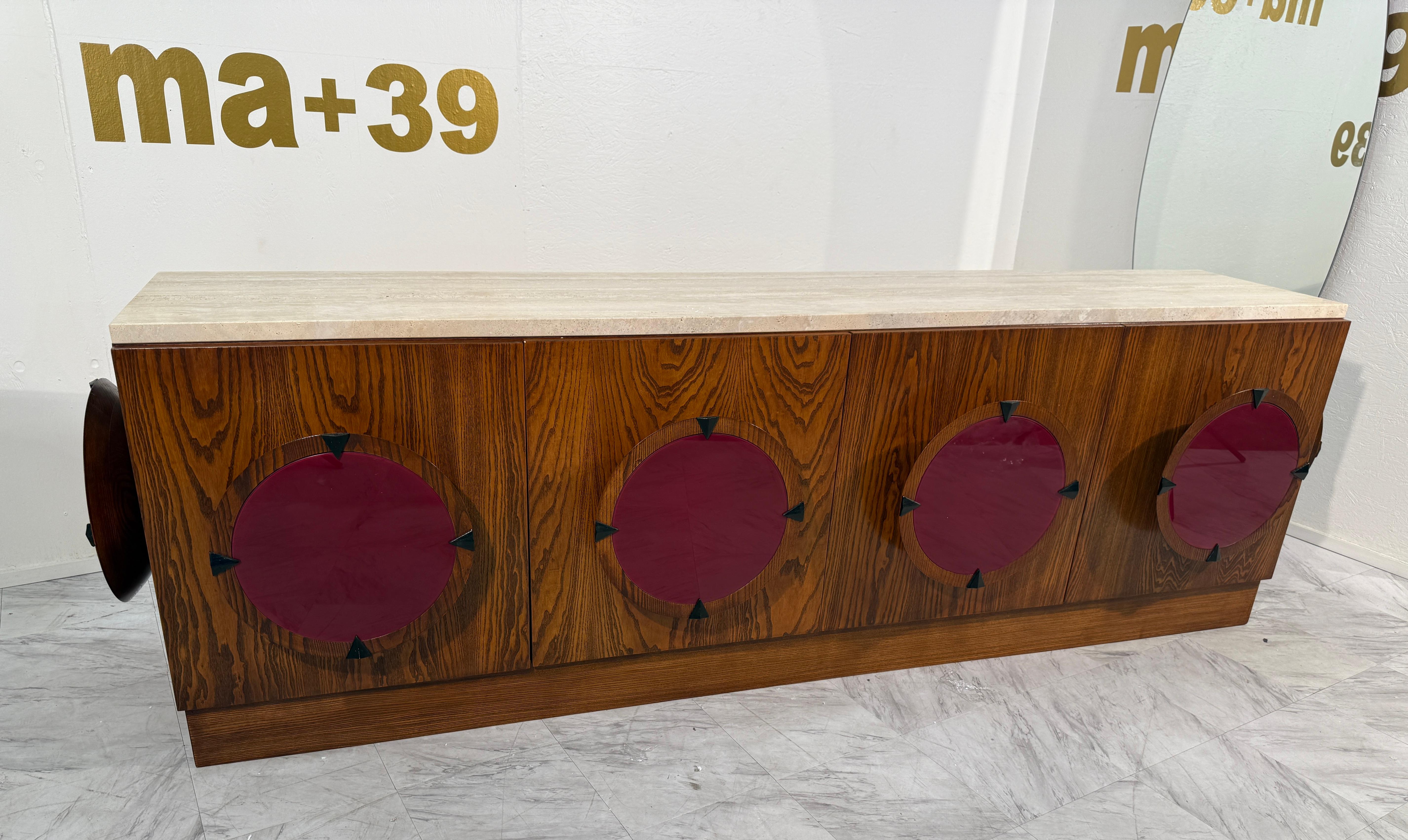 Striking Italian mid-century modern sideboard from the 1970s, featuring a unique combination of materials and bold geometric design. The piece is crafted from richly grained wood with four cabinet doors, each adorned with large circular red