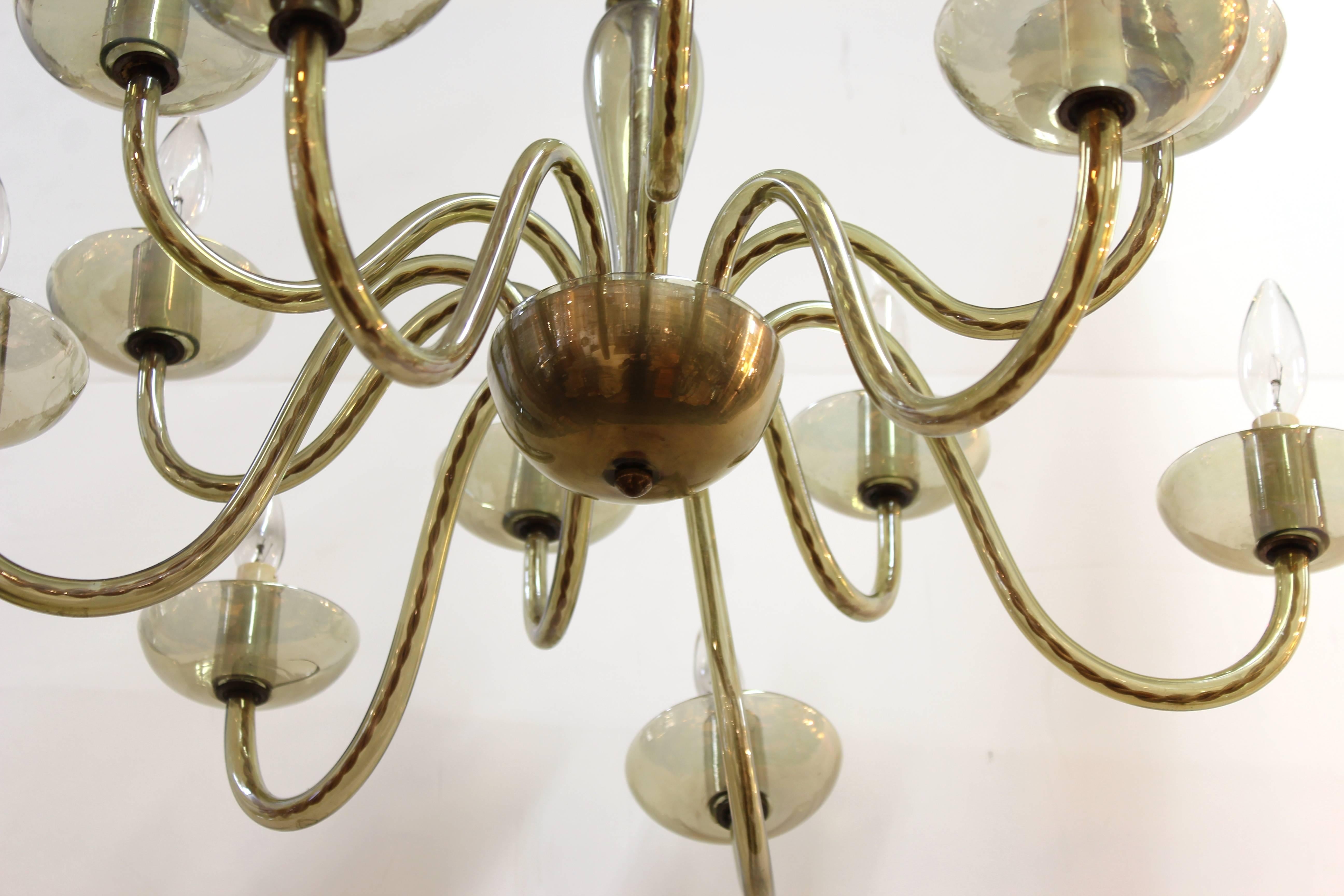 A Mid-Century Modern chandelier made in smoked glass in Italy in the mid-20th century. The piece has had visible repair work done on one of its arms and there are small cracks in one of the glass rims of another arm.