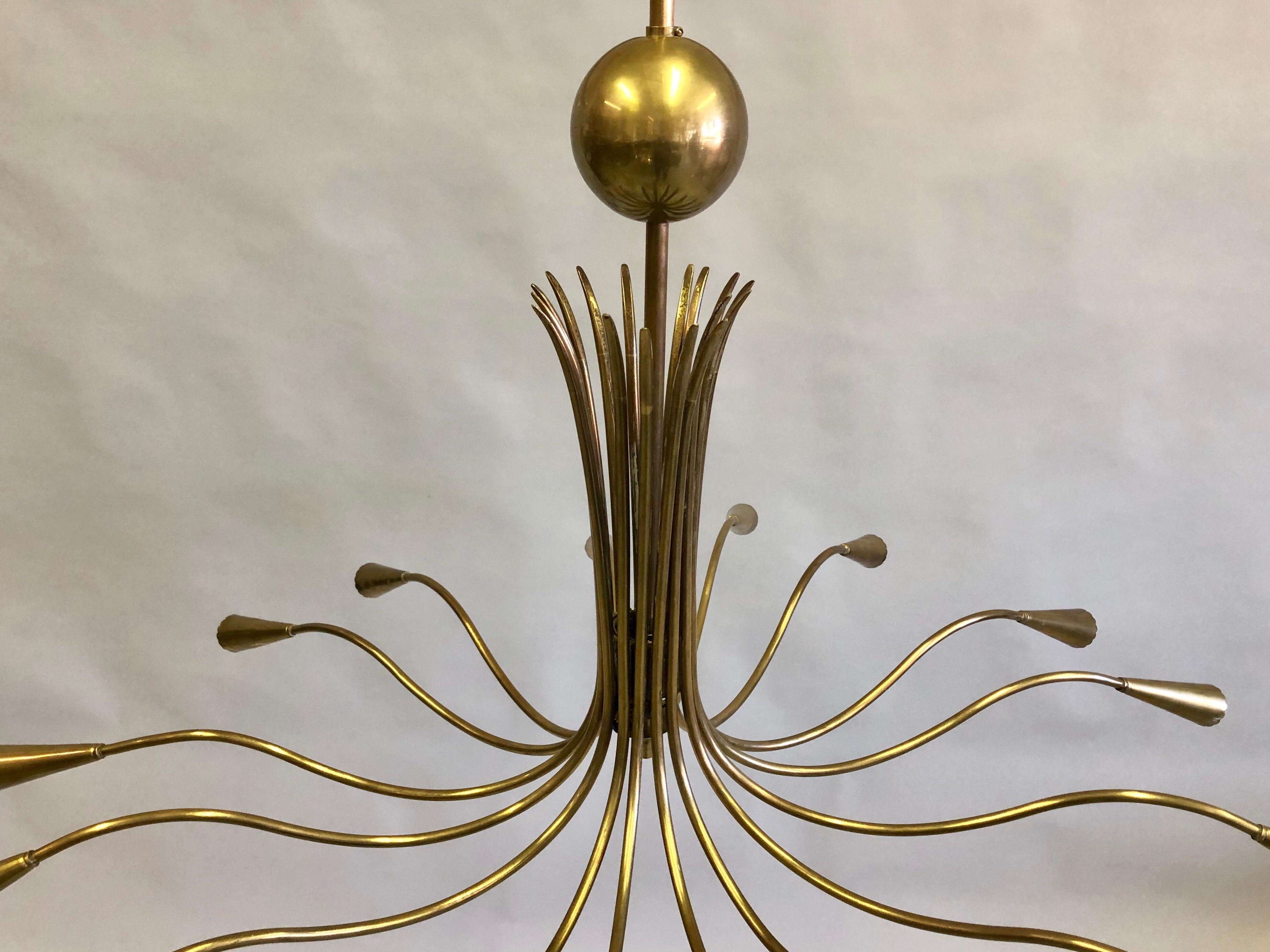 Elegant Italian Mid-Century Modern brass pendant / chandelier by Stilnovo. The chandelier is composed entirely of brass with natural antique patina and is circular / round in form with 16 arms. The piece has a sensuous gently undulating motion to