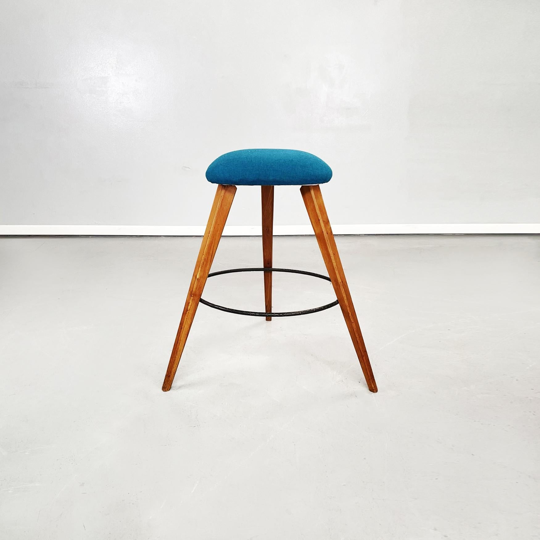 Italian Mid-Century Modern stools in wood, black iron and blue fabric, 1960s.
Pair of high stools with padded seat covered in turquoise blue fabric. The three legs are made of wood and connected by a black iron circle.

1960s.

Very good