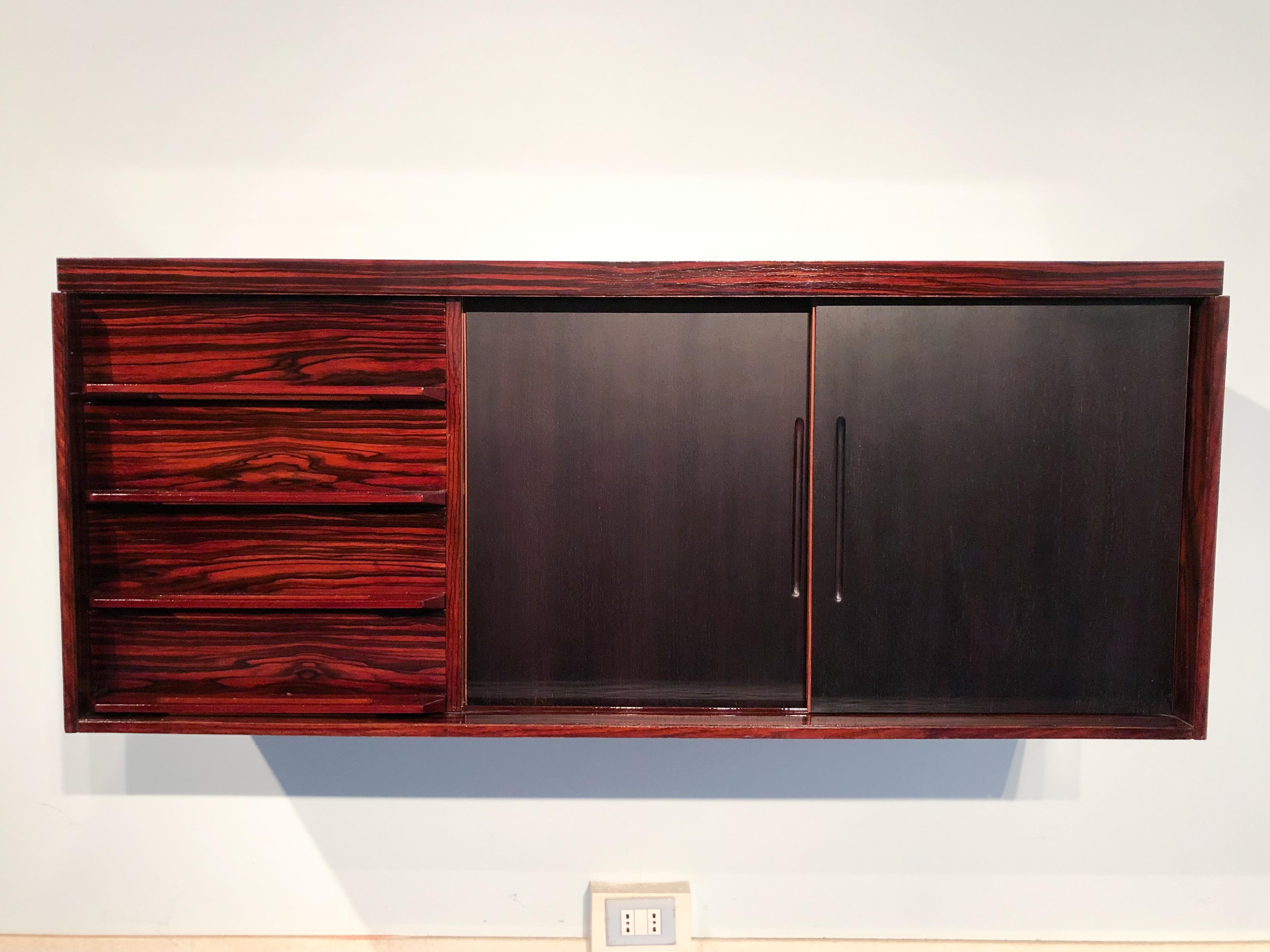Italian Mid-Century Modern wall mounted sideboard in precious Macassar ebony from the 1950s. The suspended sideboard has a very refined drawers design and maple interiors. The innovative contrast between the matte black lacquered sliding doors and