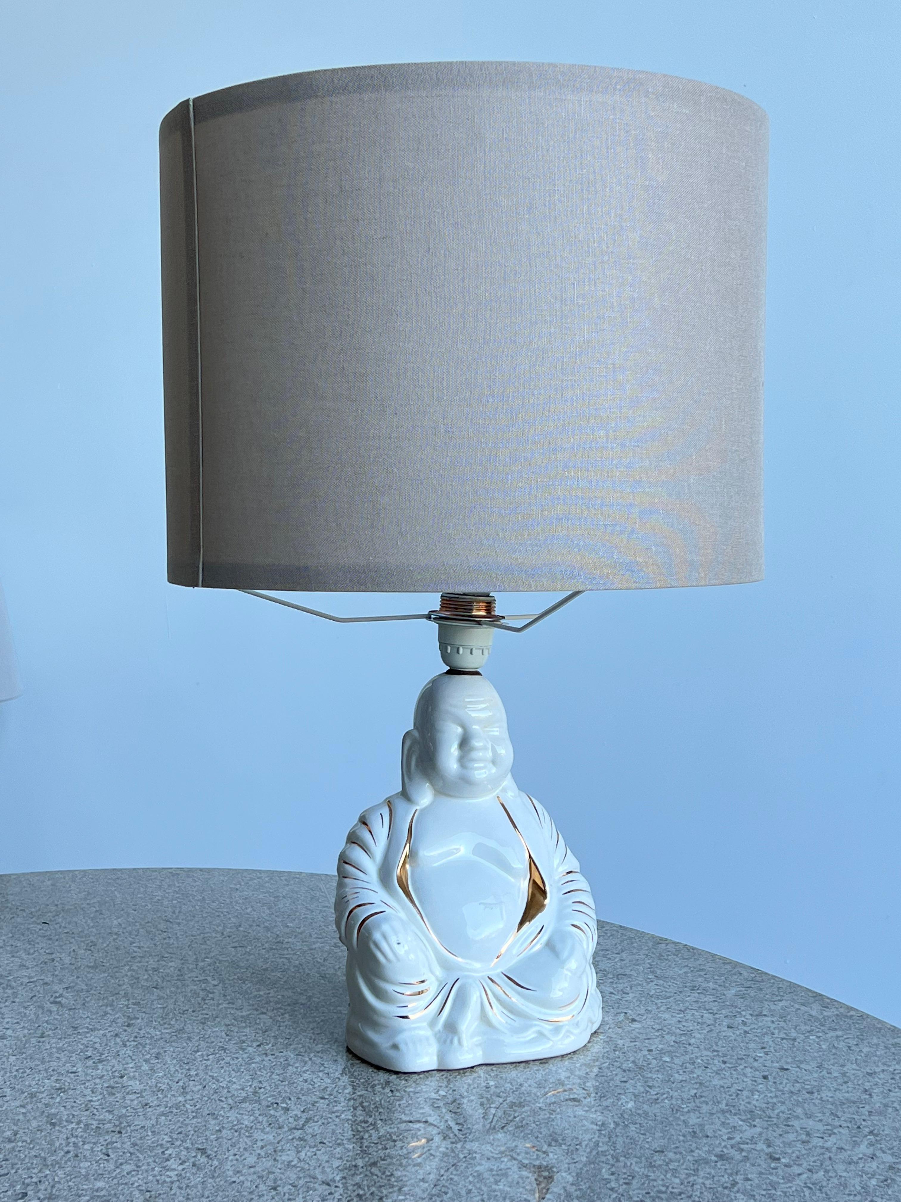 Italian mid century hand painted porcelain table lamp, Buddha shaped 1960s.
Gold hand paint porcelain Buddha lamp, the shade is been replaced with a light colour round shaped shade.
Completely rewired with nice gold cables and switch.