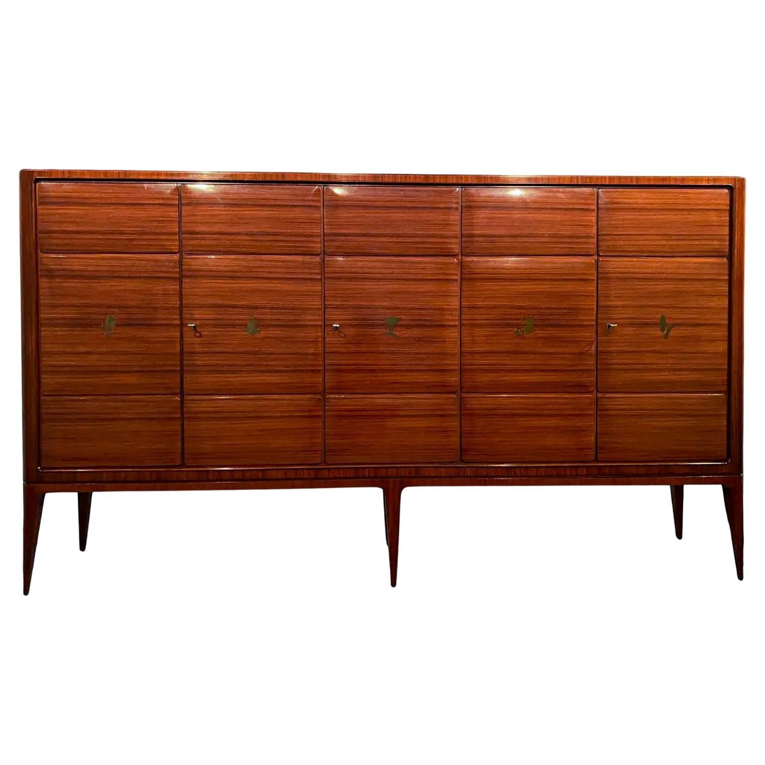Magnifica credenza italiana disegnata da Paolo Buffa negli anni '50. Il piano superiore è caratterizzato da un'impiallacciatura in legno disposta a spina di pesce. Le porte hanno tre pannelli, ognuno dei quali è impreziosito da uno splendido