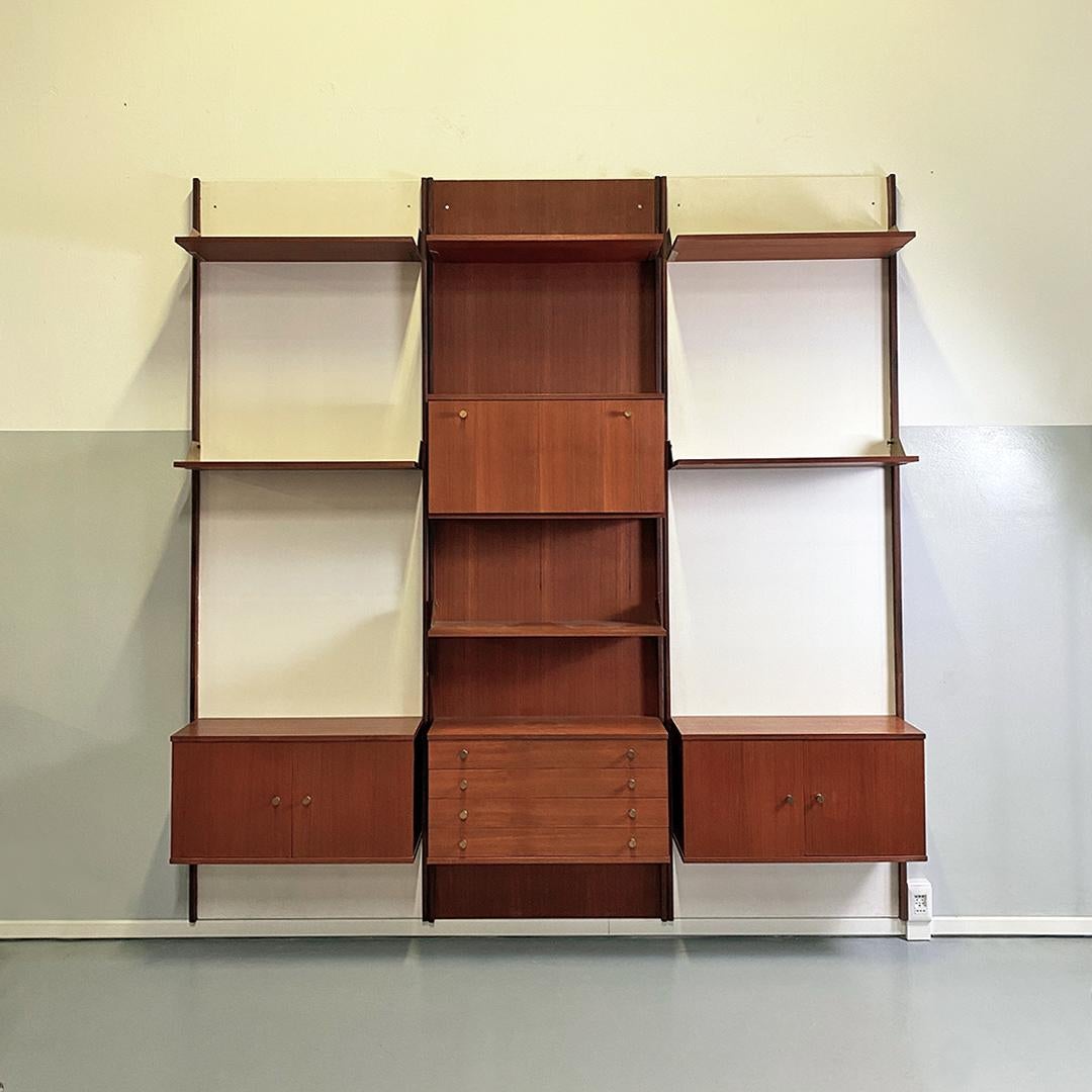 Italian Mid-Century Modern teak and brass modular wall bookcase with cabinets, 1960s
Wall bookcase, modular, completely in teak. Composed of three wall panels, two of which painted white, with uprights that form the profile of the panels, shelves