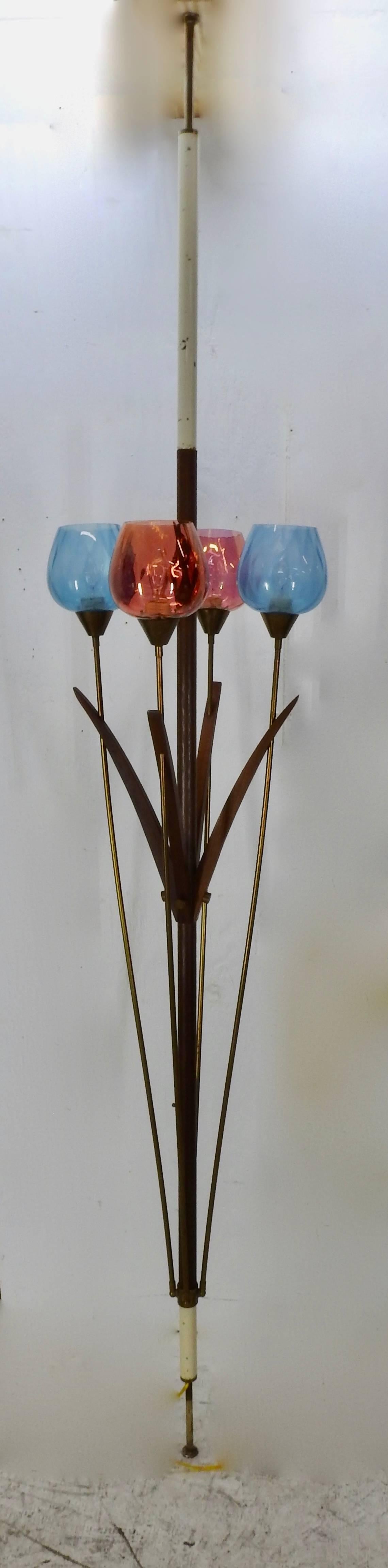 We are featuring an Italian Mid-Century Modern tension floor lamp with four lights. The stained glass shades are cranberry and turquoise. The lamp has porcelain Leviton sockets and works with more bulbs lighting with each turn of the knob. The cord