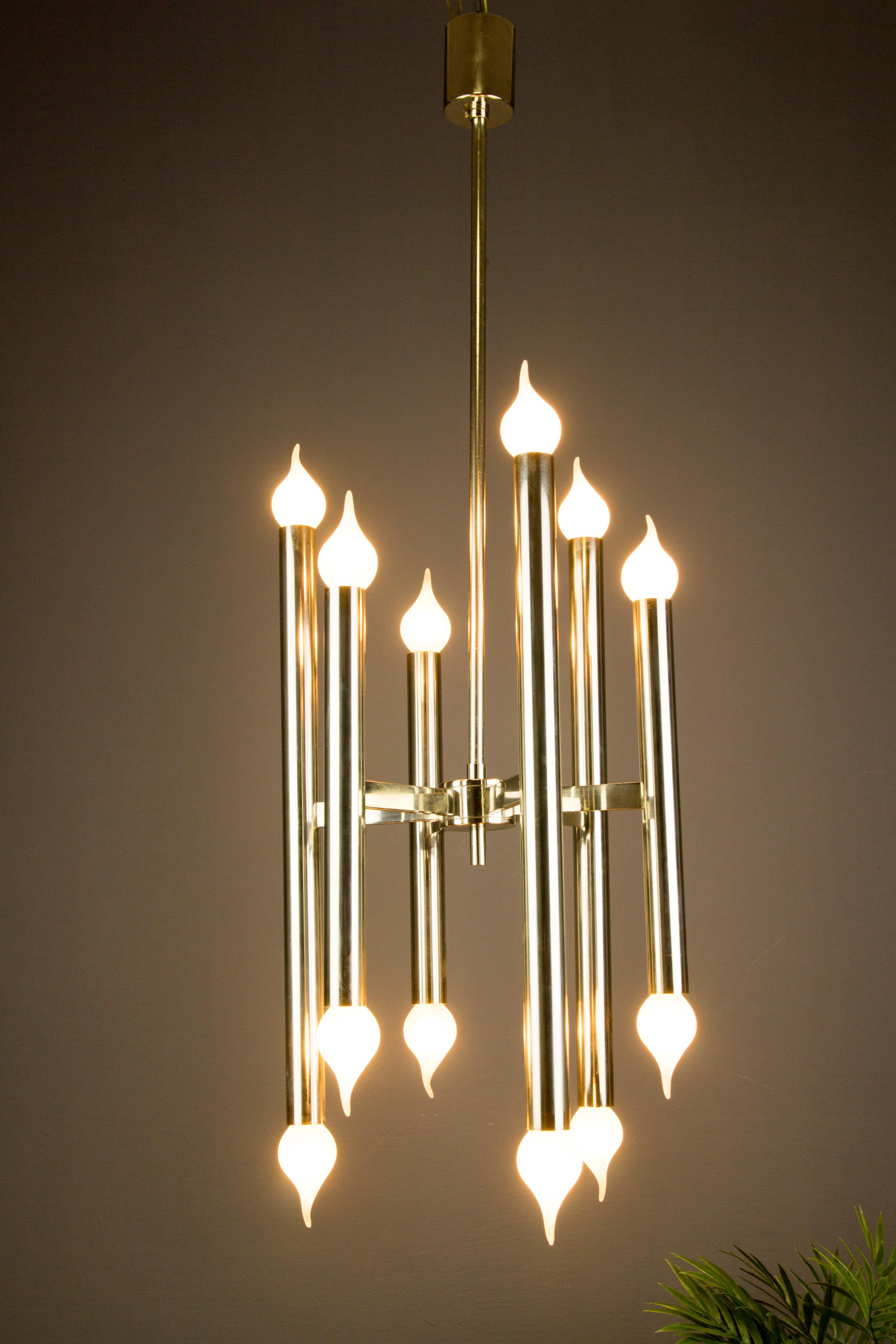 Italian chromed chandelier with twelve cylindrical lights arranged in a circular formation with six lights on the top and six on the bottom, from the 1970s.  Twelve sockets for E14 size light bulbs. This elegant Mid-Century Modern chandelier is