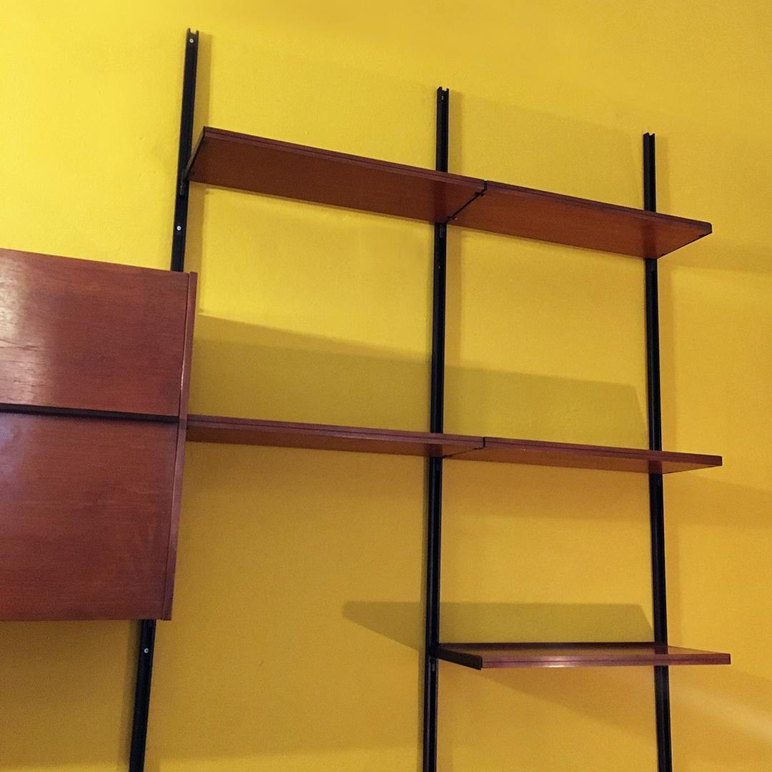 Italian Mid-Century Modern wall bookcase E22 by Osvaldo Borsani for Tecno, 1960s
Modular composition fixed on black metal uprights, with shelves, sideboard with sliding doors and drop-down bar cabinet in wood, with internal shelf and shelf in