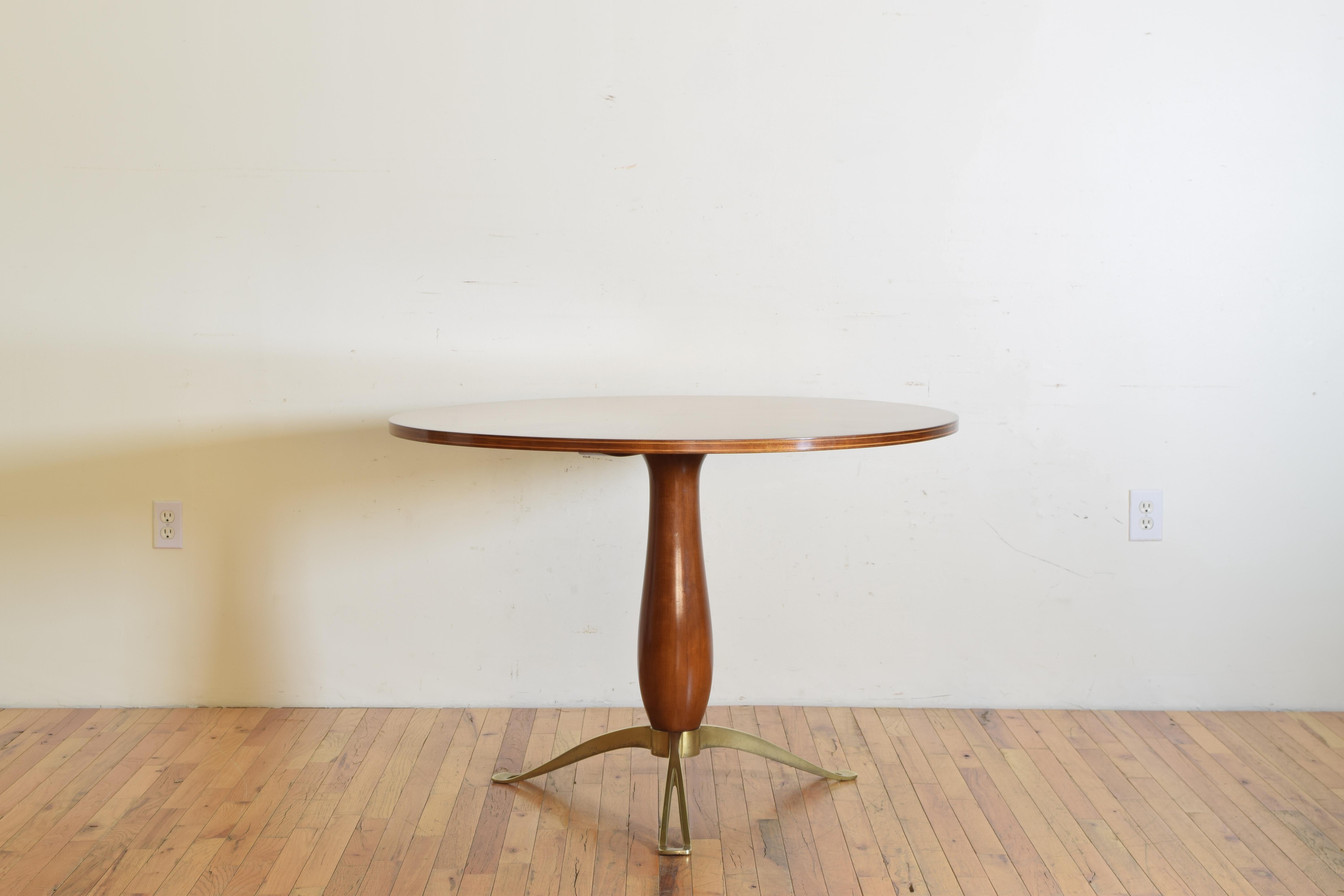 The circular walnut top with matched veneers and an inlaid band in profile above a solid walnut standard raised on shaped brass legs.