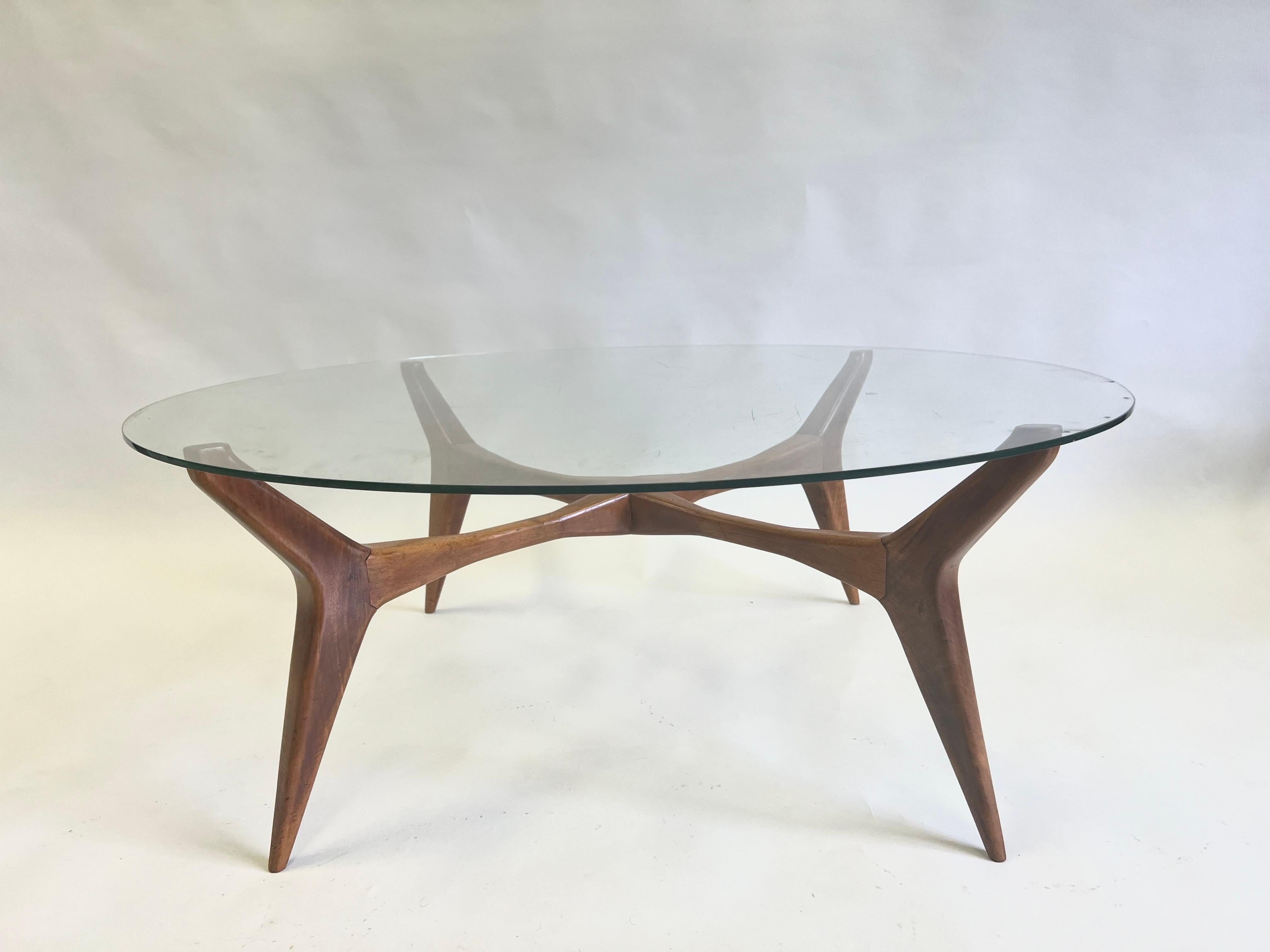 A rare and iconic Italian Mid-Century Modern Round Cocktail Table in Solid Walnut by the Italian master architect and designer Gio Ponti. The piece presents an original and bold design of 4 deeply angled and deeply tapered legs with deeply angled