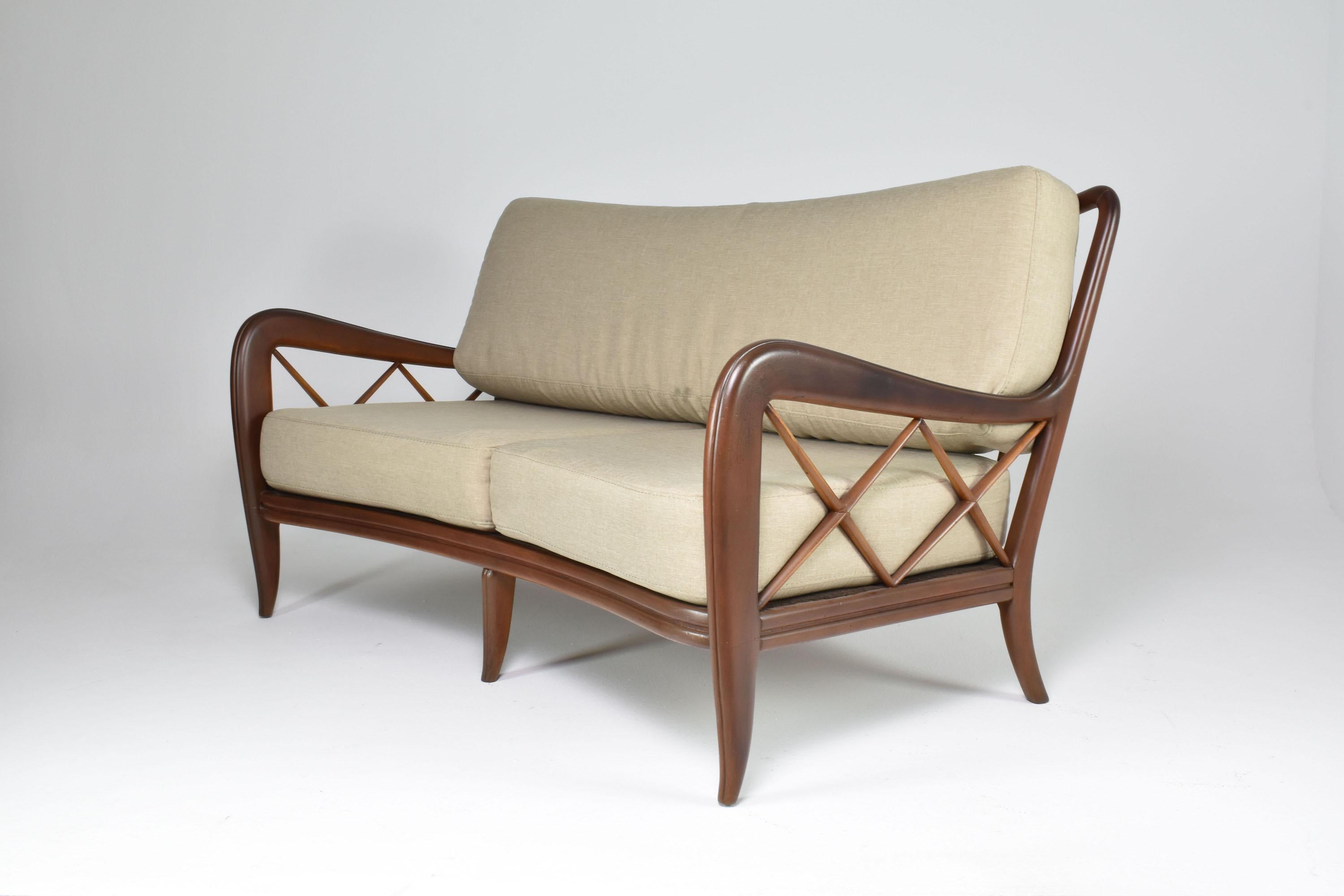 A beautiful 1950s Italian cream two-seater sofa attributed to Paolo Buffa with a structure crafted of bent walnut that adds to its durability and strength. One of the standout features of this collectable vintage sofa is the crossed wooden panels on