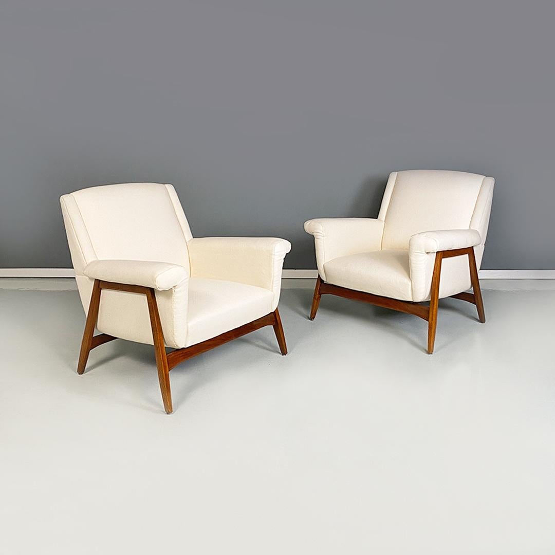 Italian mid century modern white cotton and solid beech pair of armchairs, 1960s.
Pair of armchairs with rectangular section frame and legs in walnut-stained solid beech and with seat and armrests fully padded and upholstered in new white