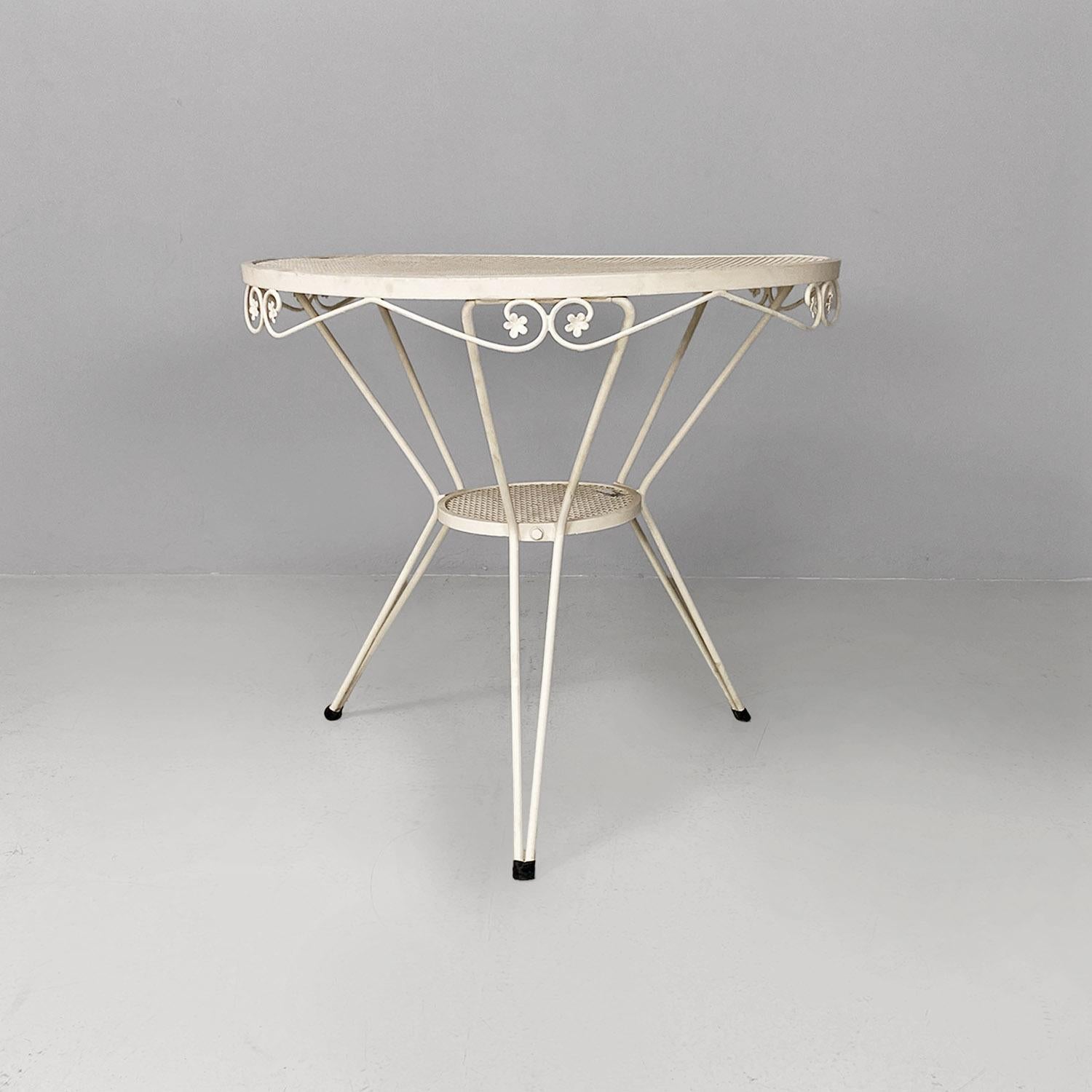 Tavolo da giardino rotondo in ferro bianco con decorazioni floreali, 1960.
Tavolo da pranzo in ferro verniciato bianco con piano rotondo forato, sotto il quale si trova un secondo piano più piccolo, da cui partono le tre gambe tubolari. Il bordo del