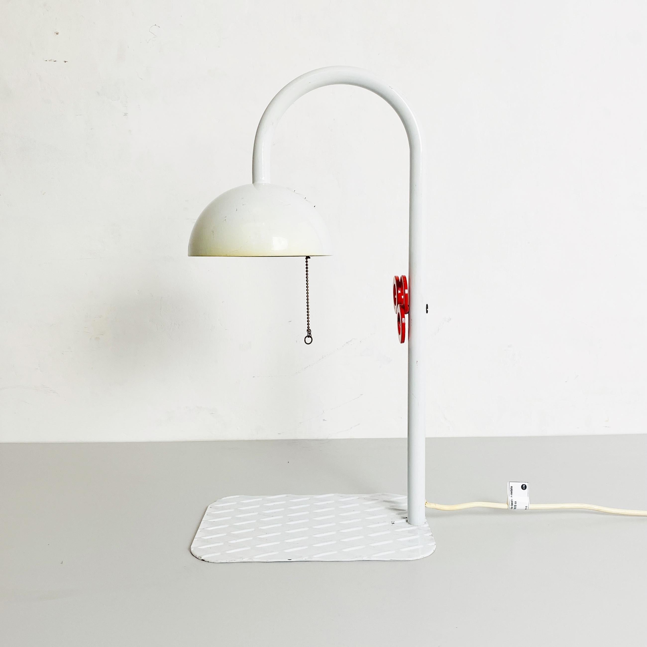 White metal table lamp by L'isola che non c'è, 1980s
White metal table lamp with red knob on the handle, flat metal base with diamond pattern and white lampshade with red perforated metal closure and chain switch. Produced by the italian company