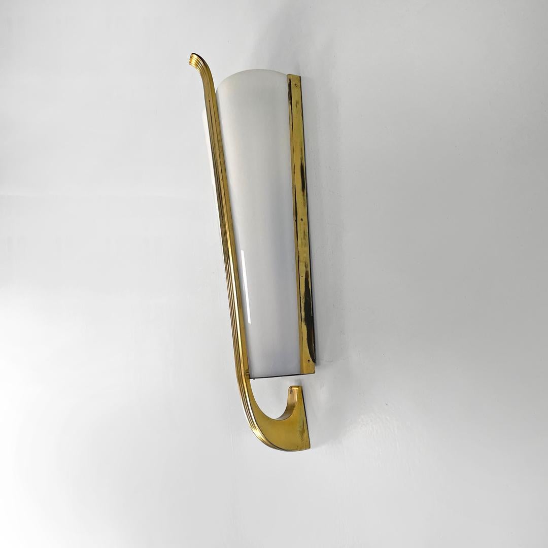 Applique italienne mid-century modern en plexiglas blanc et métal doré, années 1950.
Applique à base conique et de forme allongée. L'abat-jour se développe en longueur et est en plexiglas blanc, tandis que la structure finement décorée est en métal