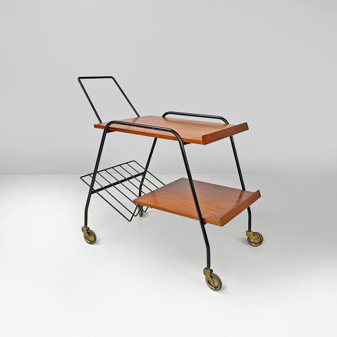 Italian mid-century modern wood and black metal trolley with brass wheels, 1960s
Trolley with two wooden shelves. The structure is made of black painted metal rods, and it comprises the carrying handle, the four legs and two side handles on the