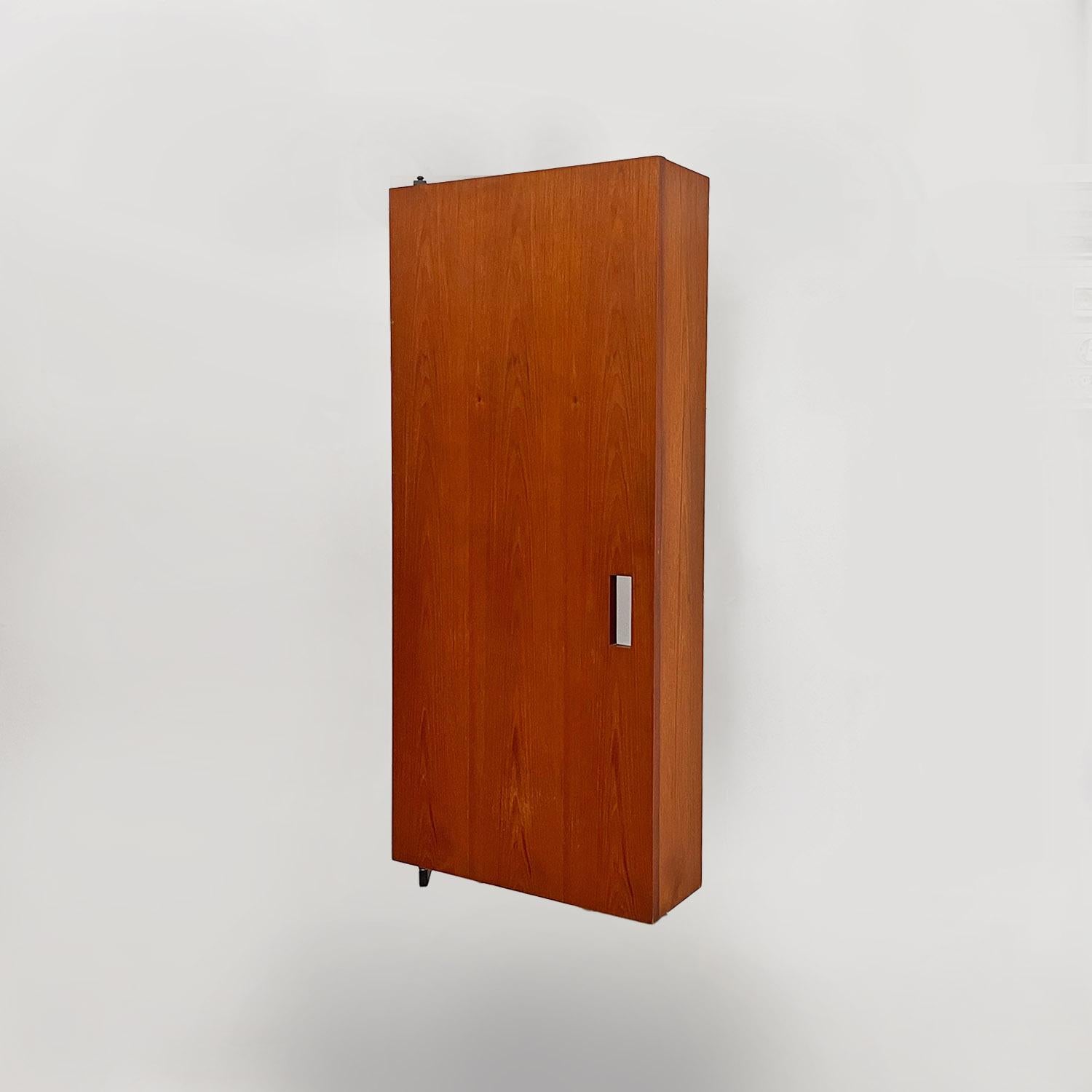 Armadio a muro in legno e metallo nero della metà del secolo scorso con ganci, anni '60.
L'armadio a muro è sostenuto da un'asta di ferro nero a forma di C, che lo tiene ancorato alla parete e permette di aprire la parte in legno per riporre vestiti