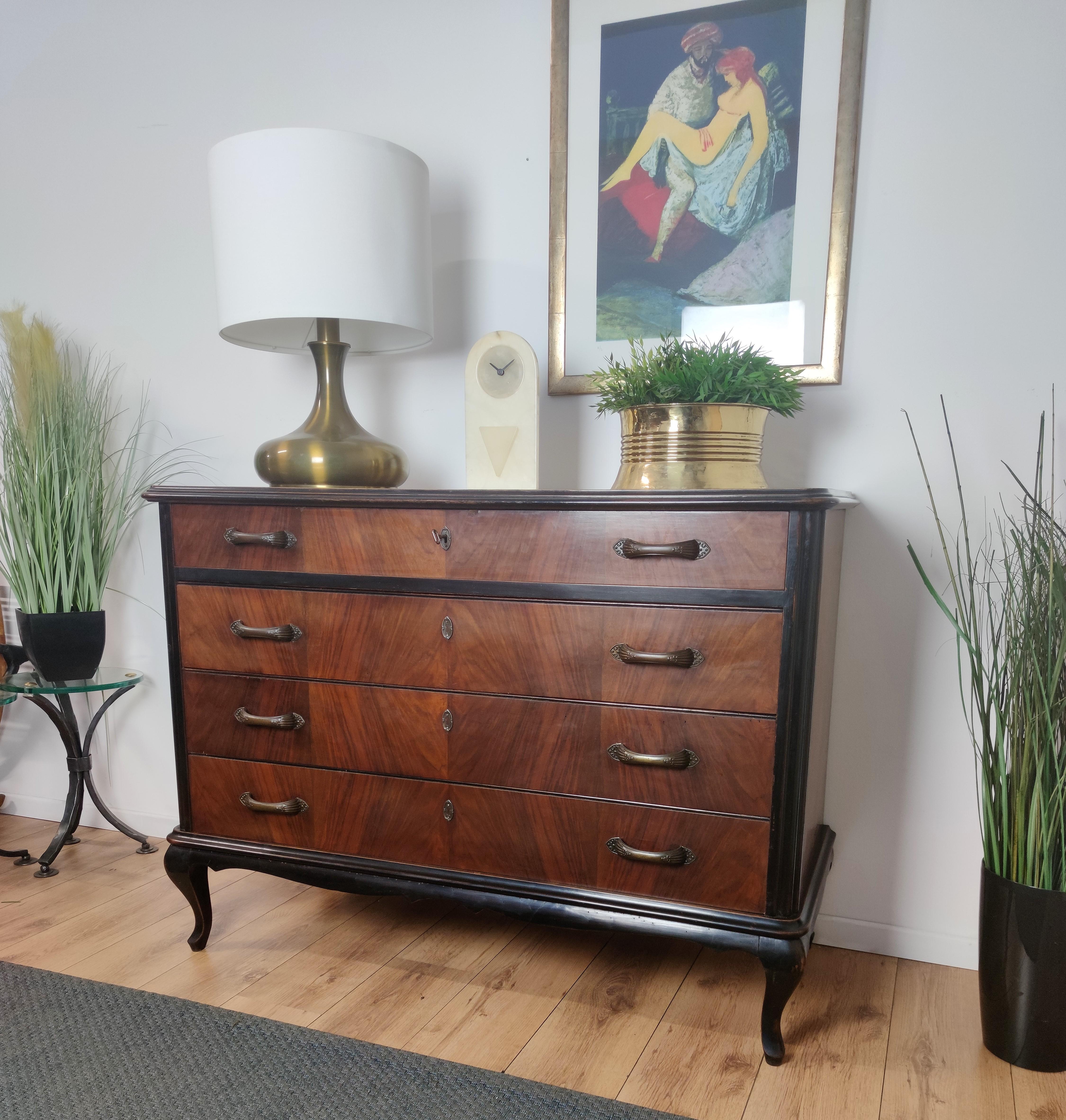 Beautiful Italian 1960s dresser, commode or chest of 4 drawers in elegant and classic wood worked according its veneer natural graining with beveled top, gilt brass handles and black wooden frame standing on 4 bracket feet. 

This charming piece