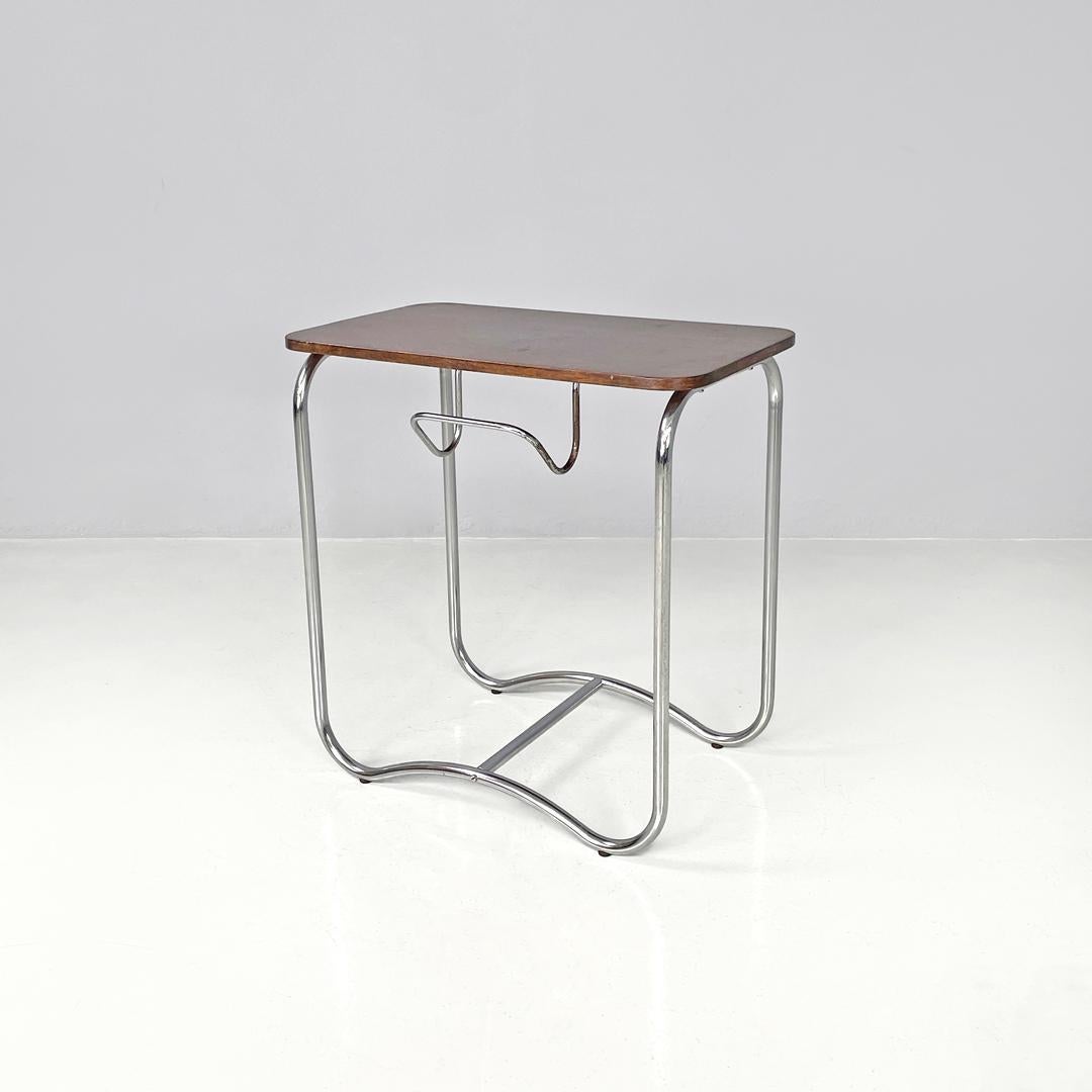 Table basse italienne en bois et métal de style The Moderns avec crochet à journaux années 1950
Table basse avec plateau rectangulaire en bois. La structure est faite de tiges de métal chromé, les quatre pieds s'étendent jusqu'au sol pour ensuite