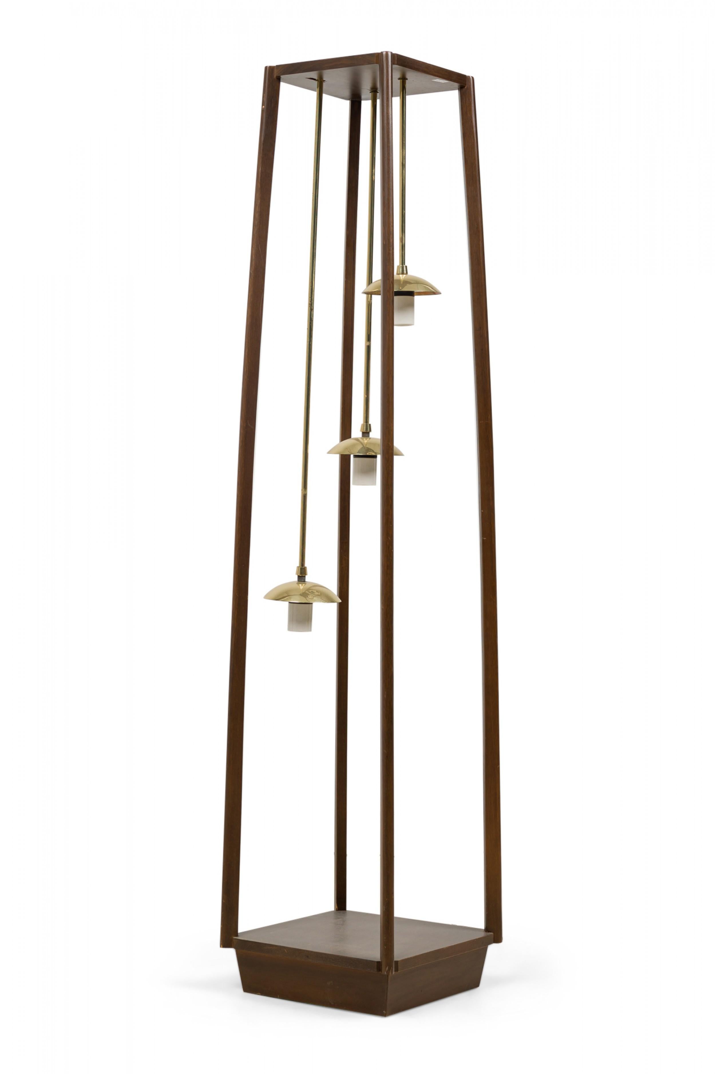 Italian Mid-Century Modern floor lamp featuring a wooden frame that tapers slightly to the top, suspending three brass pendant lights at stepped heights, each having a polished brass dome shade over a cylindrical frosted glass light.