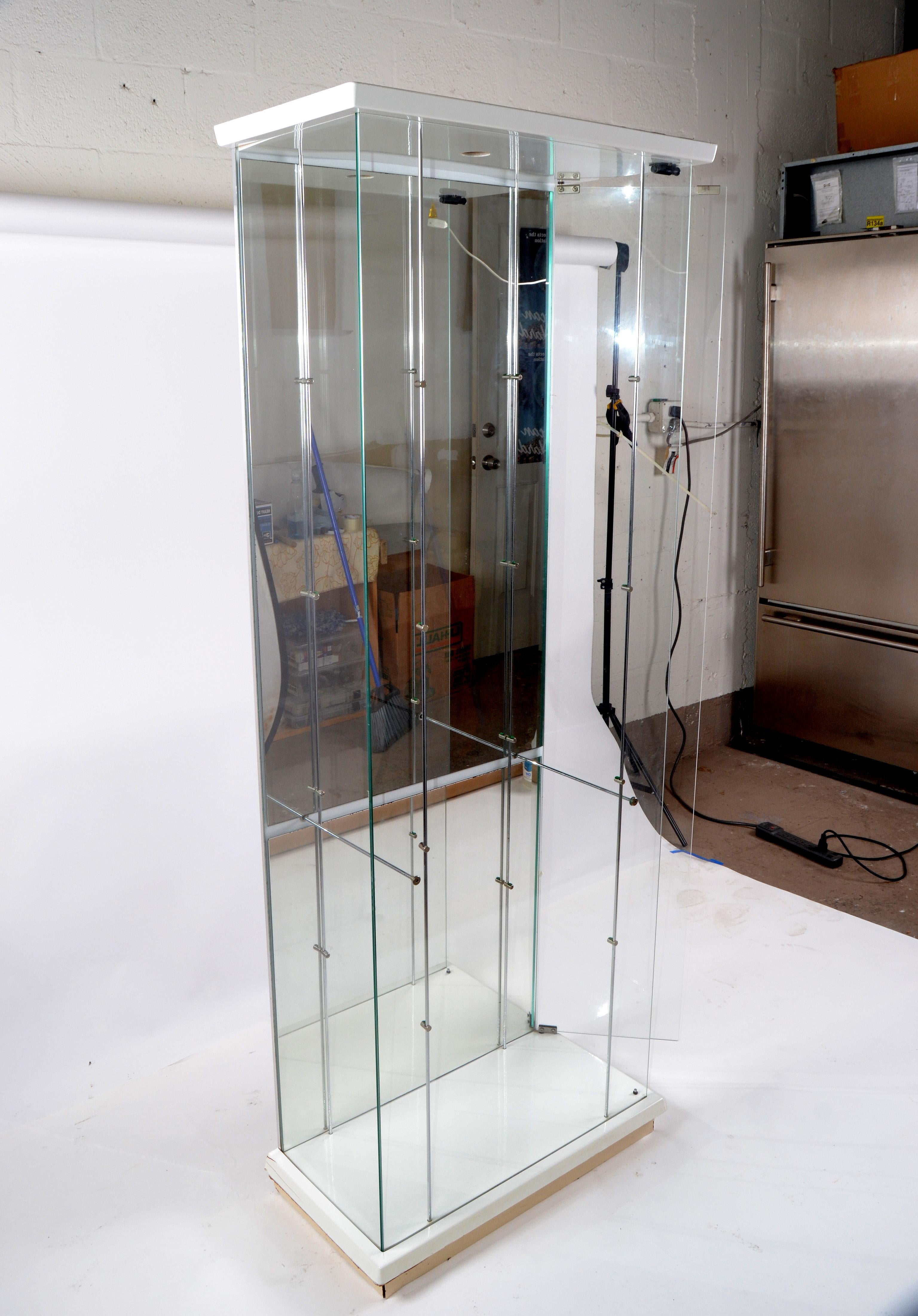 Six feet tall and four-level glass shelves Mid-Century Modern showcase made in Italy.
Wooden base and tall glass and chrome column display or storage case.
The door is at the side and works easy with a push on magnetic closure.
Labeled on the