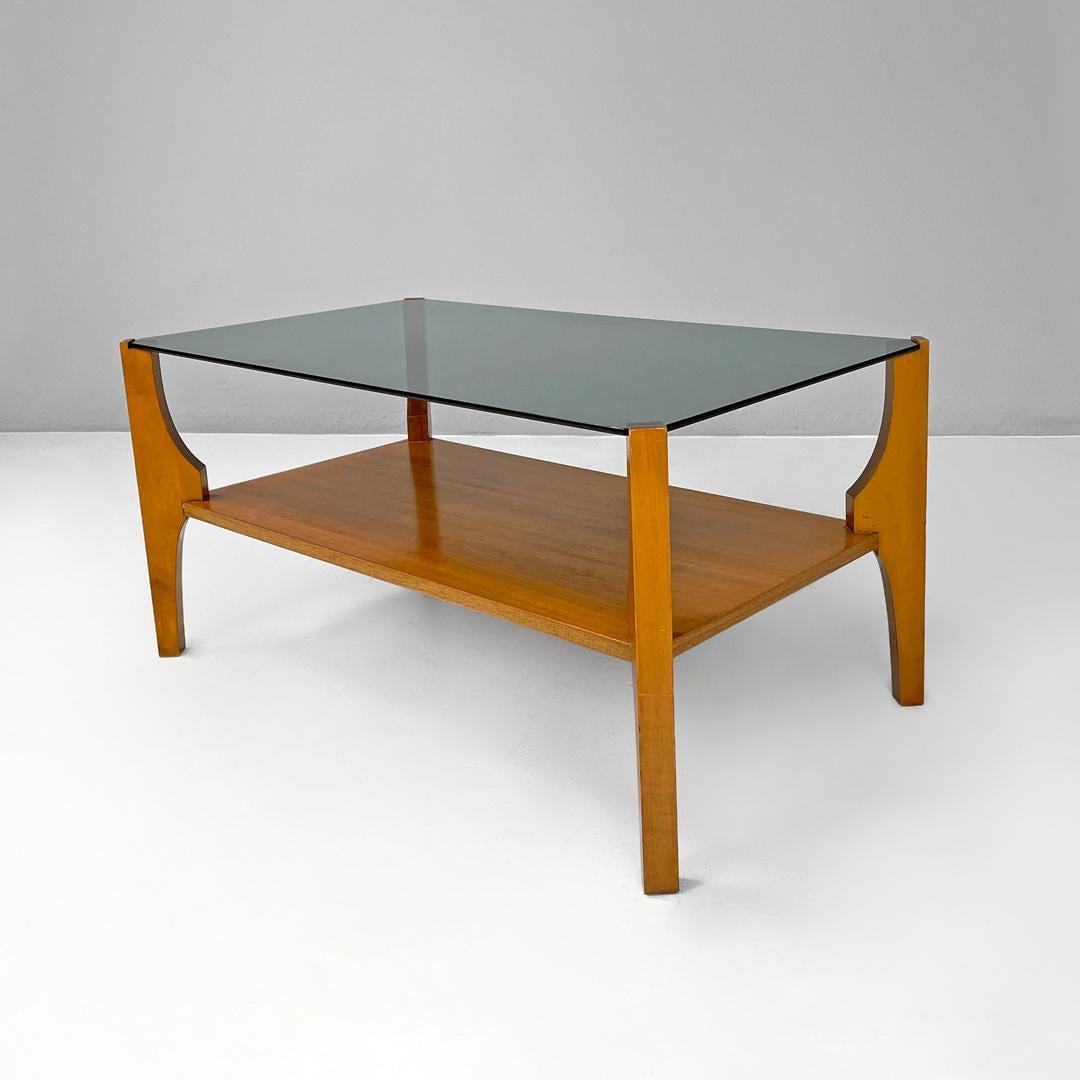 Italian mid-century modern wooden coffee table with smoked grey glass top, 1960s
Coffee table with rectangular smoked glass top. The structure is made of wood, the four legs with a rectangular section support the top at the corners, they widen