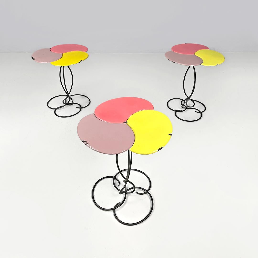 Tavolino italiano di metà secolo in ferro battuto con smalto rosa giallo, anni '50
Set di tre tavolini con base rotonda. La struttura è realizzata in tondino di ferro battuto verniciato di nero, con una parte superiore arrotondata composta da tre